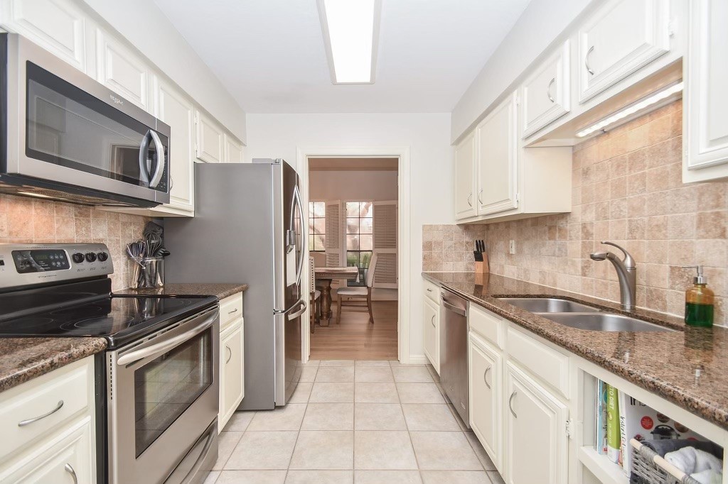 GORGEOUS kitchen features granite countertops, white cabinets, stainless steel appliances and tile backsplash!