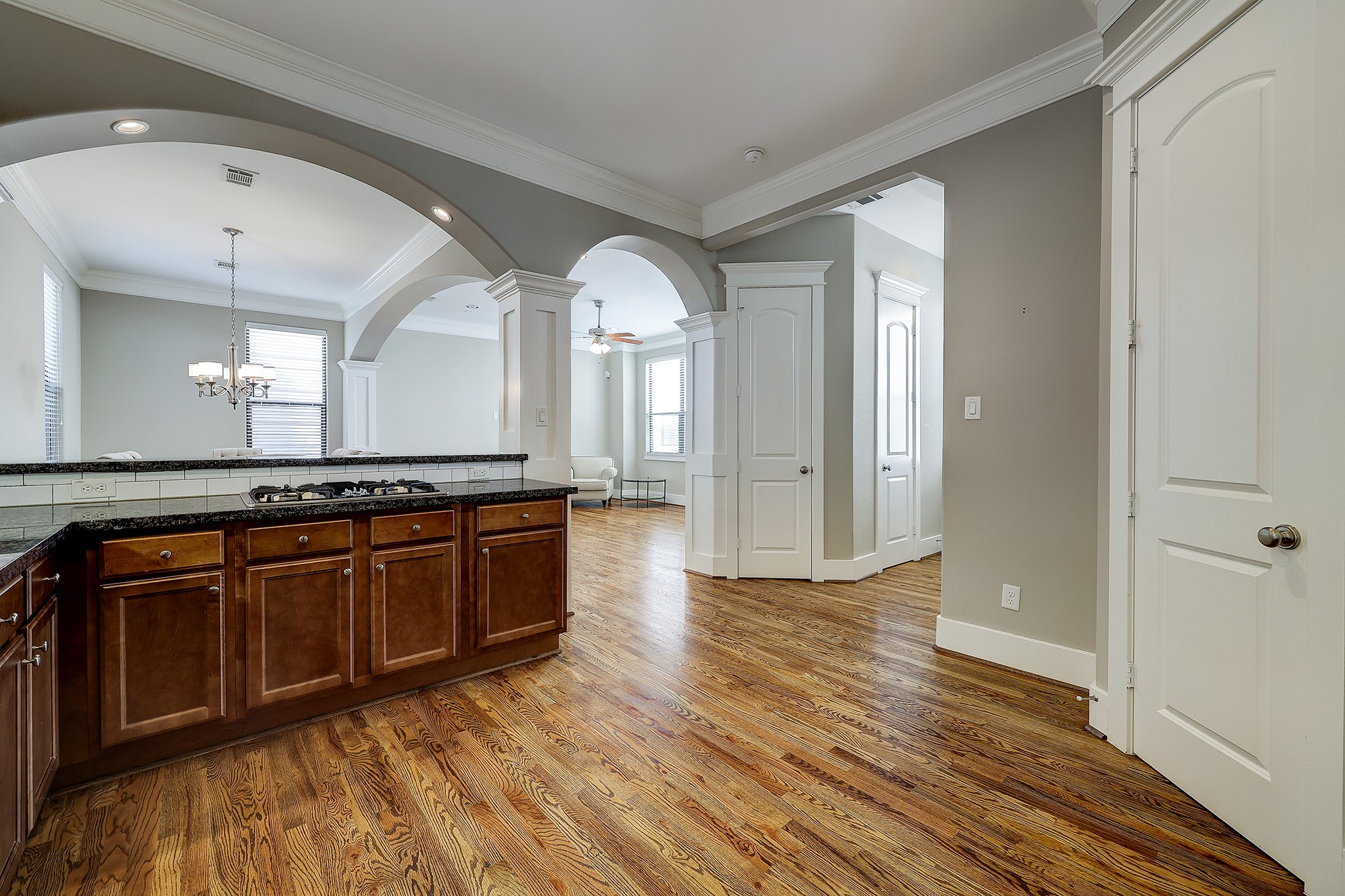 Follow the arches to the living area with plenty of natural lighting, crown molding, ceiling fan and more hardwood flooring.