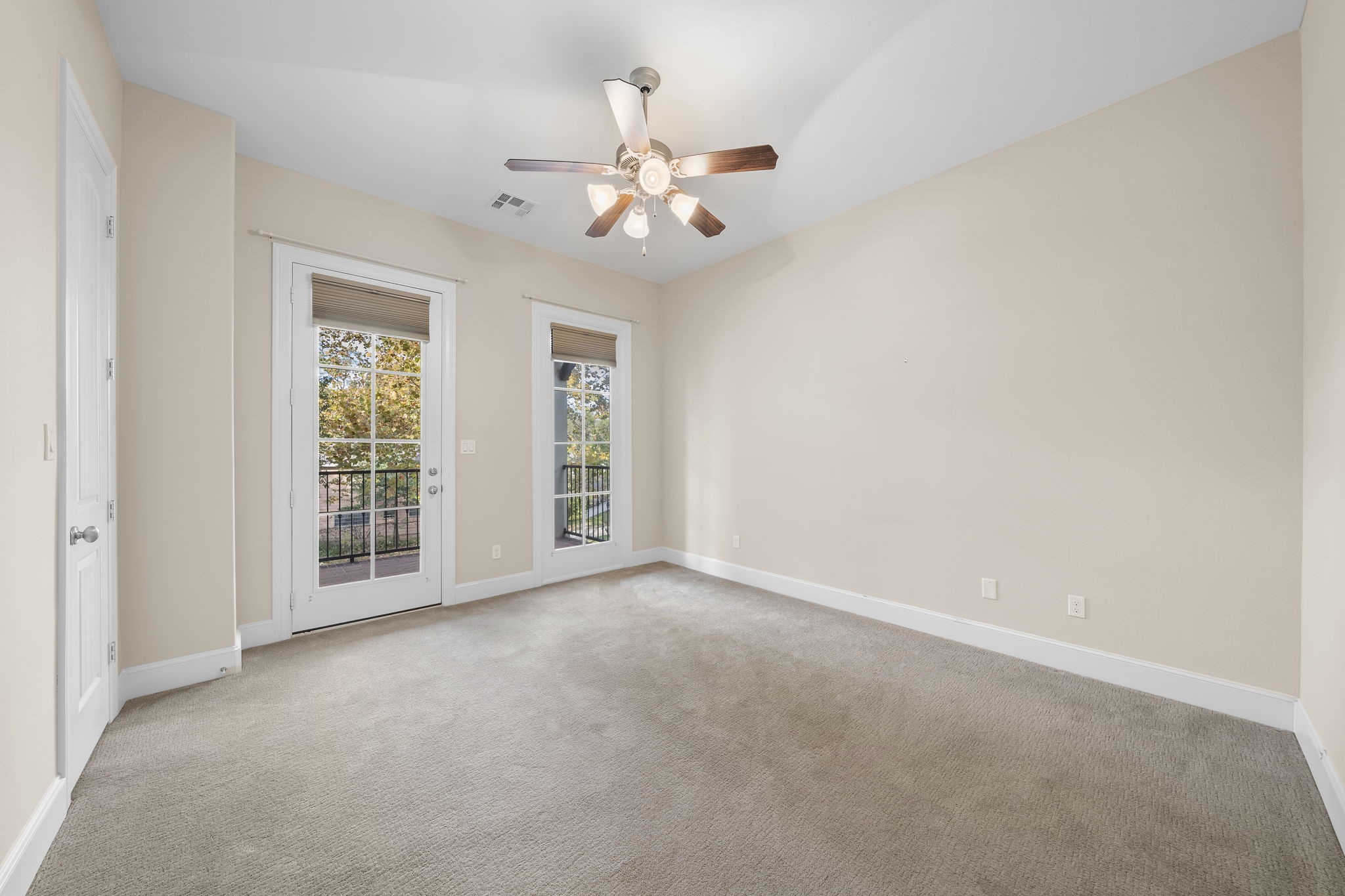 This spacious secondary bedroom is fitted with carpeted flooring, its own ensuite bath, a walk-in closet, and a covered balcony that frames delightful neighborhood views of the Nicholson Hike and Bike Trail.