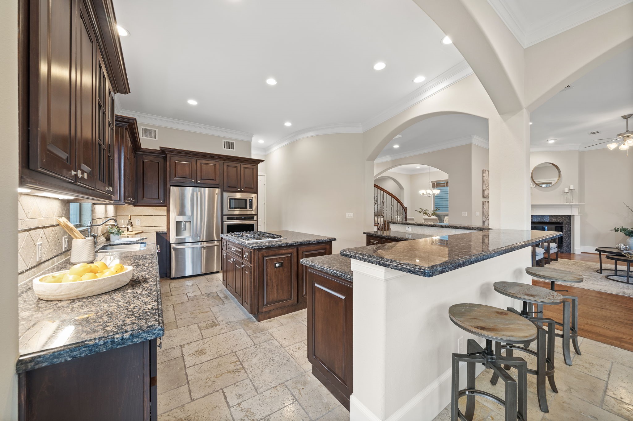 The generous open kitchen is a chef's delight, appointed with granite countertops, two breakfast bars, stainless steel appliances, a spacious island, excellent lighting, and a stunning tile backsplash. Find abundant storage space courtesy of the walk-in pantry and numerous custom cabinetry.