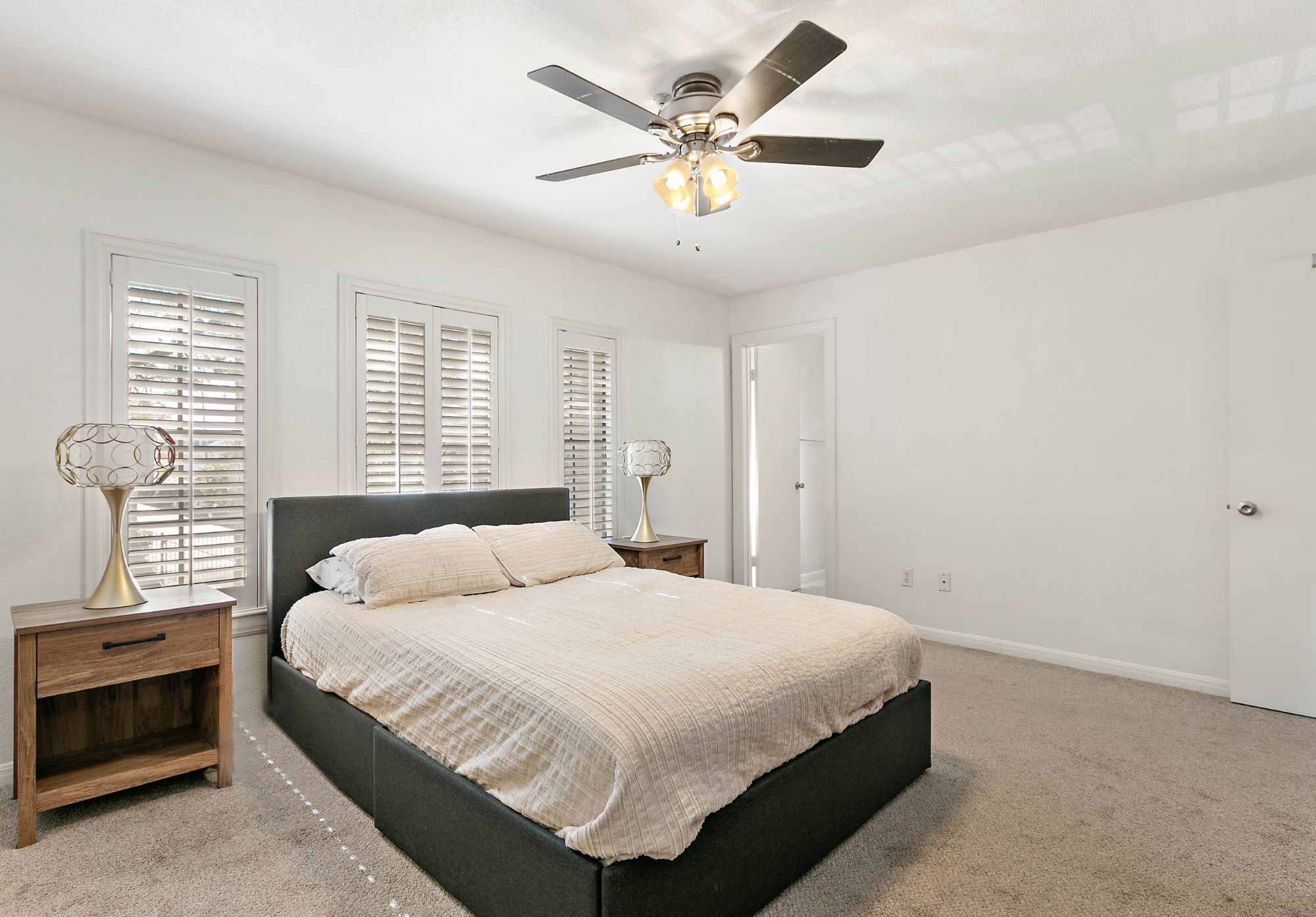 Primary bedroom enjoys Plantation shutters, plush carpet & a ceiling fan.