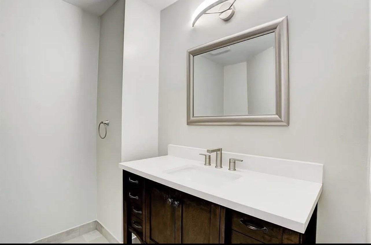 The half-bath downstairs is ideal for visiting family and friends! Features include an updated vanity with crisp white counters, brushed nickel fixtured, a framed mirror and luxe lighting.