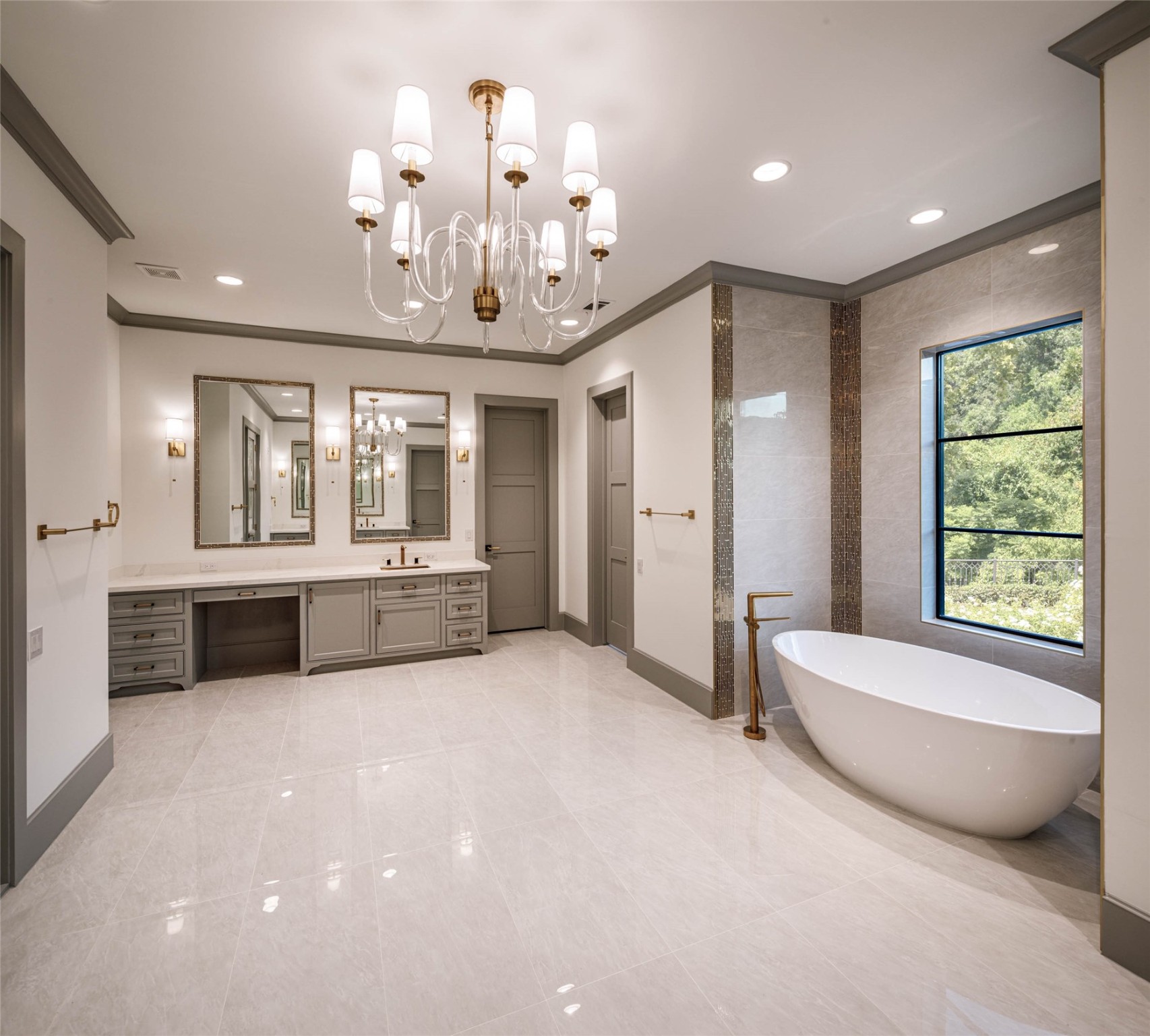 Primary bathroom with HERS side. Make-up vanity, her separate dressing area and water closet. . Porcelain soaking tub under a window with West exposure,  Designer polished hardware, framed mirrors with elegant tile details, wall sconces and custom built-ins