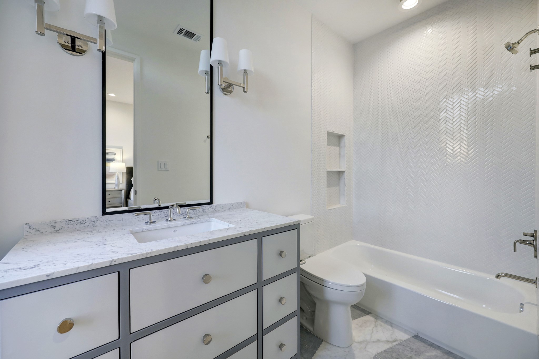 Bathroom #2  Every bathroom is this home is gorgeous!  Custom cabinet, slab marble counter, undermount sink, high end plumbing fixtures, framed mirror, pendent lights, glassy finish subway tile in a herringbone pattern surround the tub/shower. and more ..  Absolutely stunning!!
