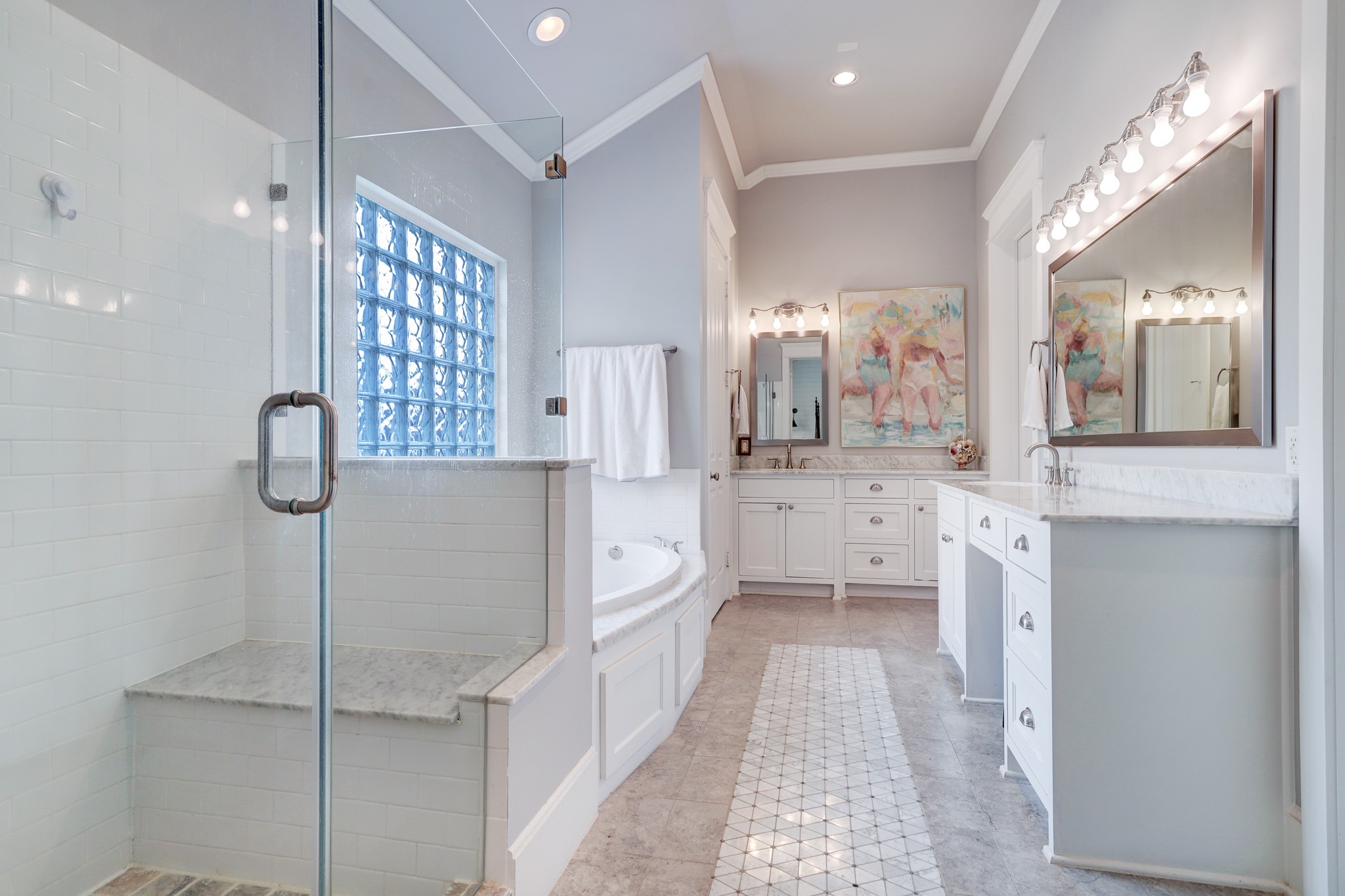 The primary bathroom features dual vanities with marble counter tops, a walk-in shower with built-in bench, a comfortable bathtub, separate water closet, and two entrances to the primary closet.