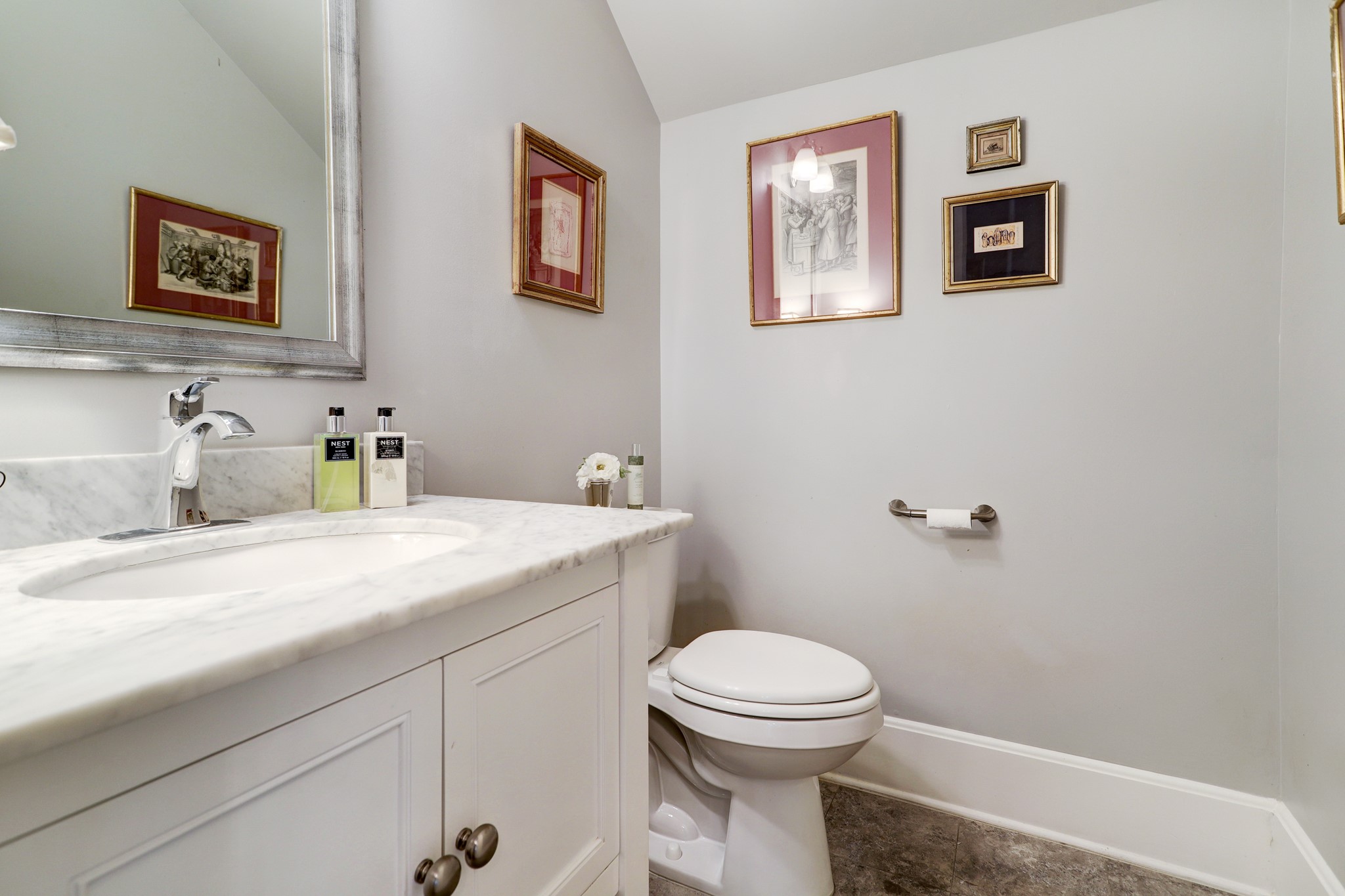 Located off of the foyer is a powder bathroom with beautiful marble counter tops, tile flooring, and under sink storage.