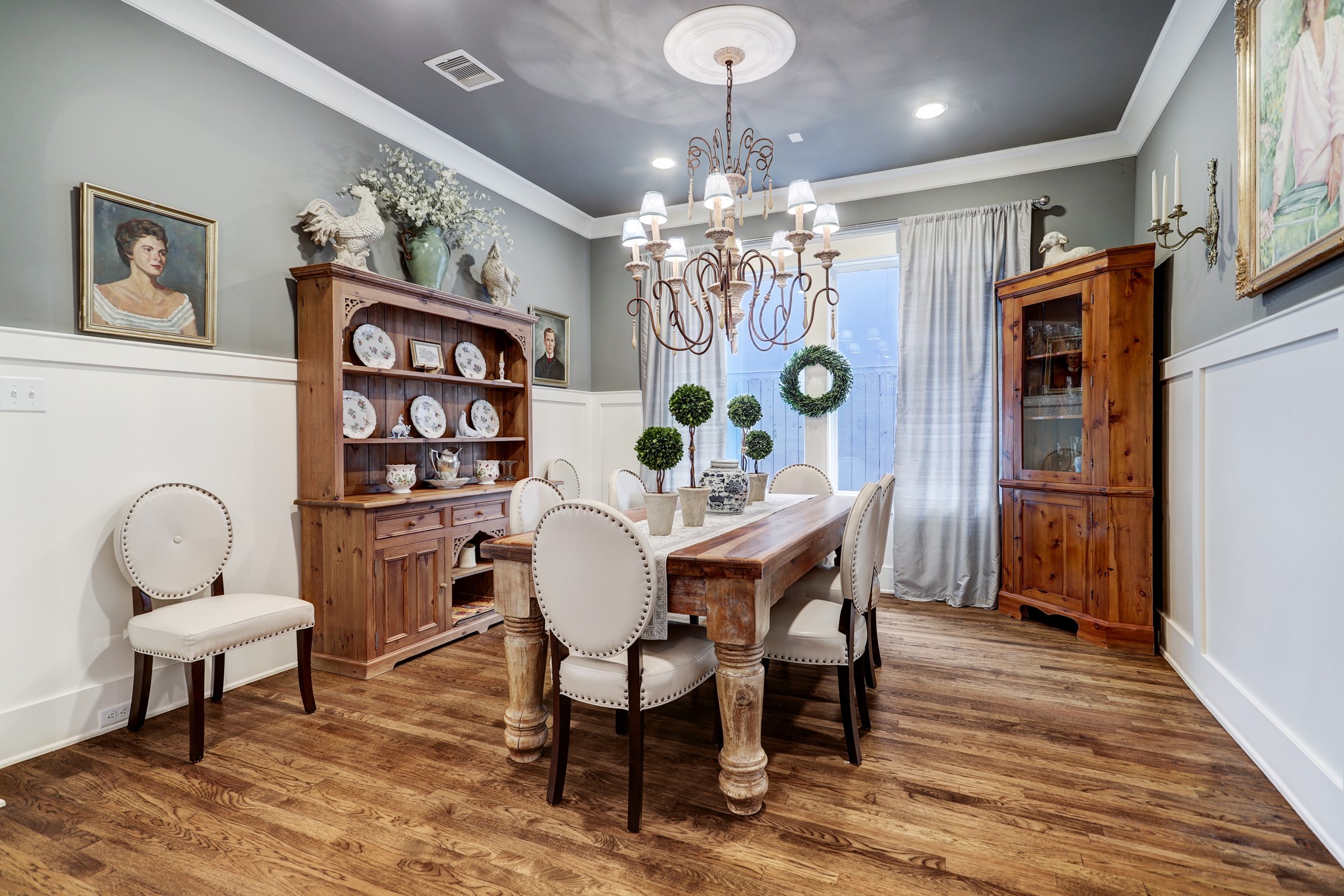 This spacious formal dining room features wainscoted walls, high ceilings, and large windows that bring an abundance of natural light into the space.