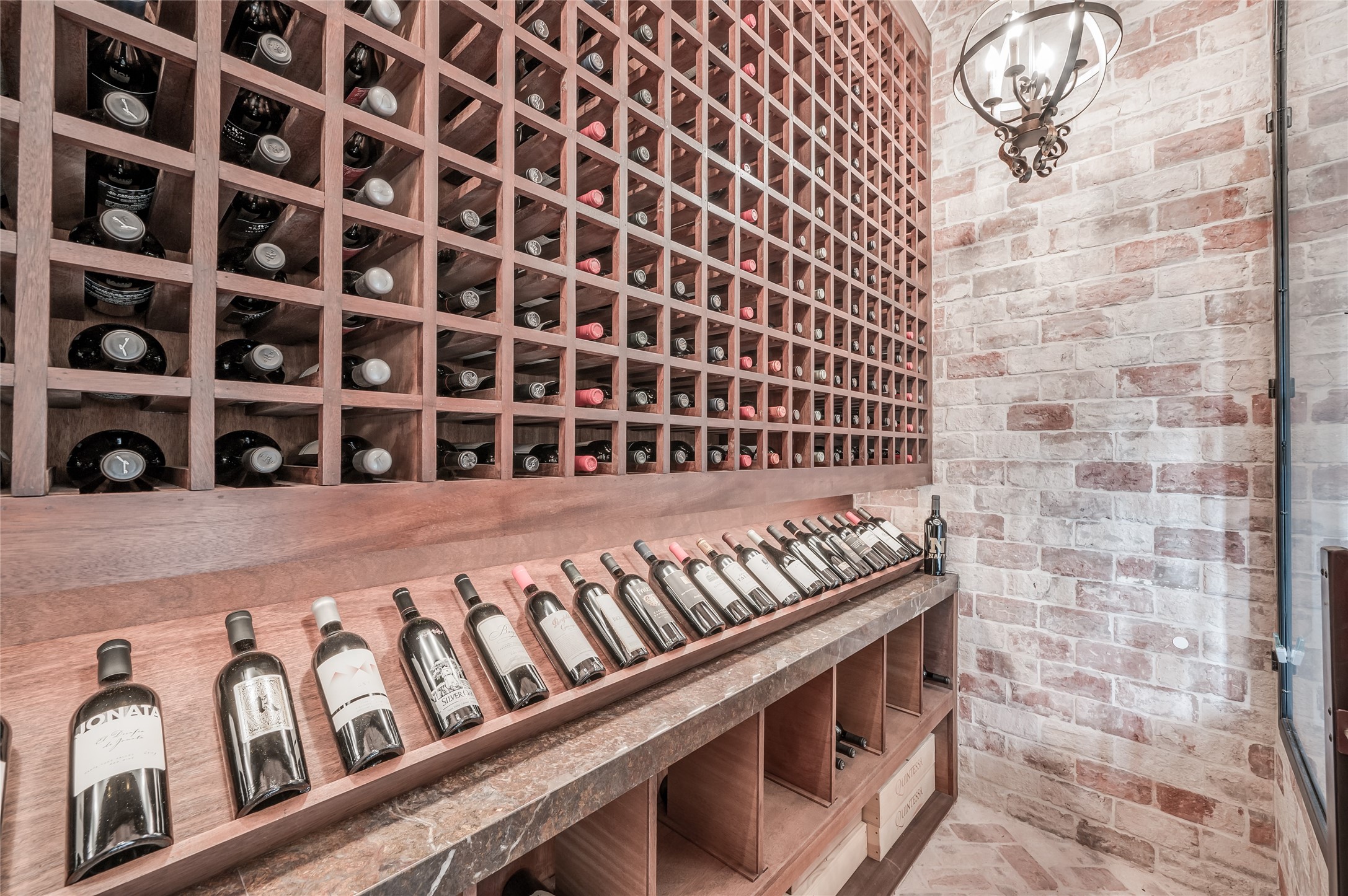 [Climate-Controlled Wine Vault]
Behind a glass and bronzed-steel door and arched window, the wine vault features a brick wall and floor, and storage for approximately 700 bottles.