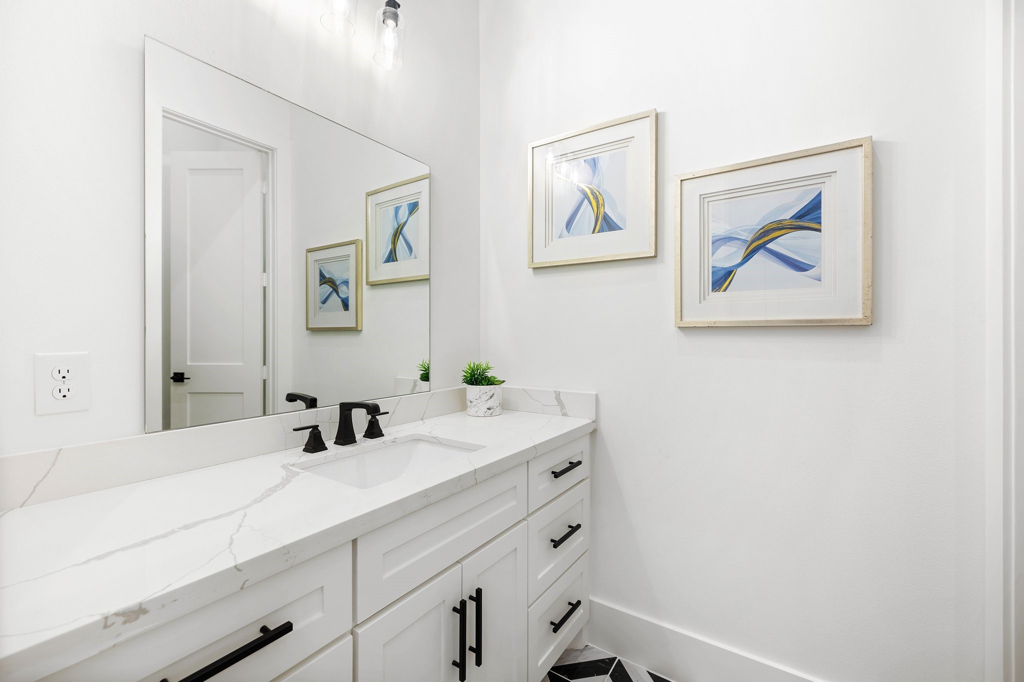 The stylish downstairs powder bathroom is adorned with chic black and white tiles, creating a modern yet timeless ambiance. The thoughtful design extends to a separate lavatory, providing added privacy.