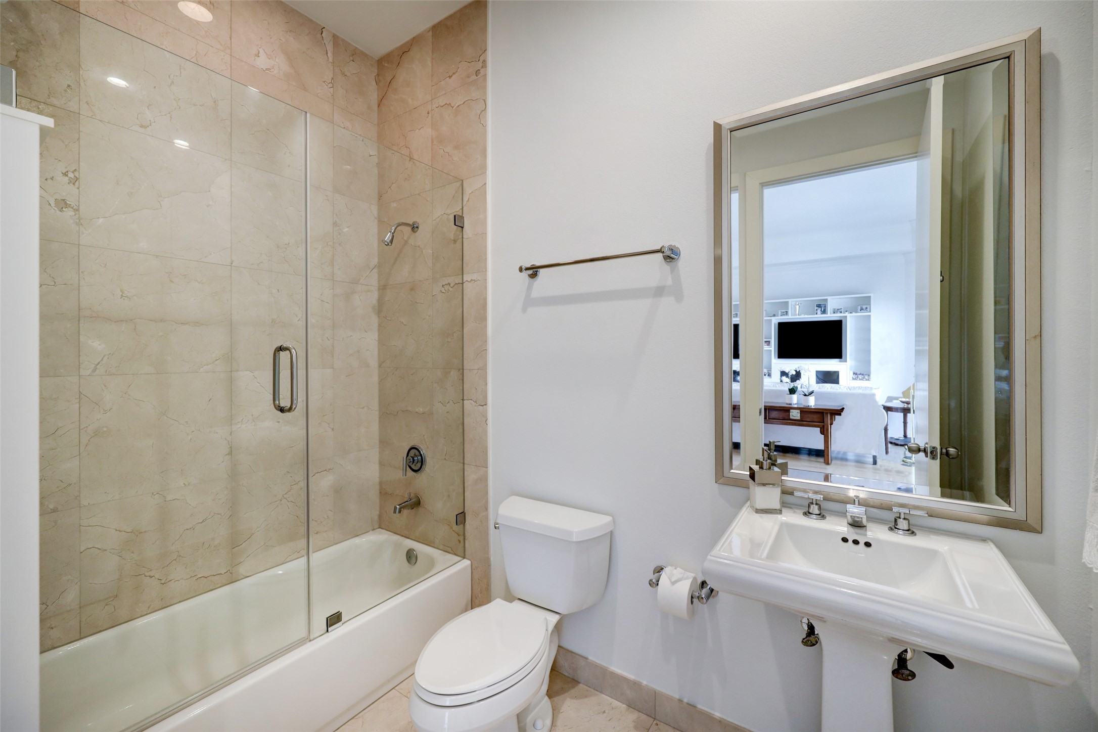 Full bath with seamless glass tub/shower and marble surround.