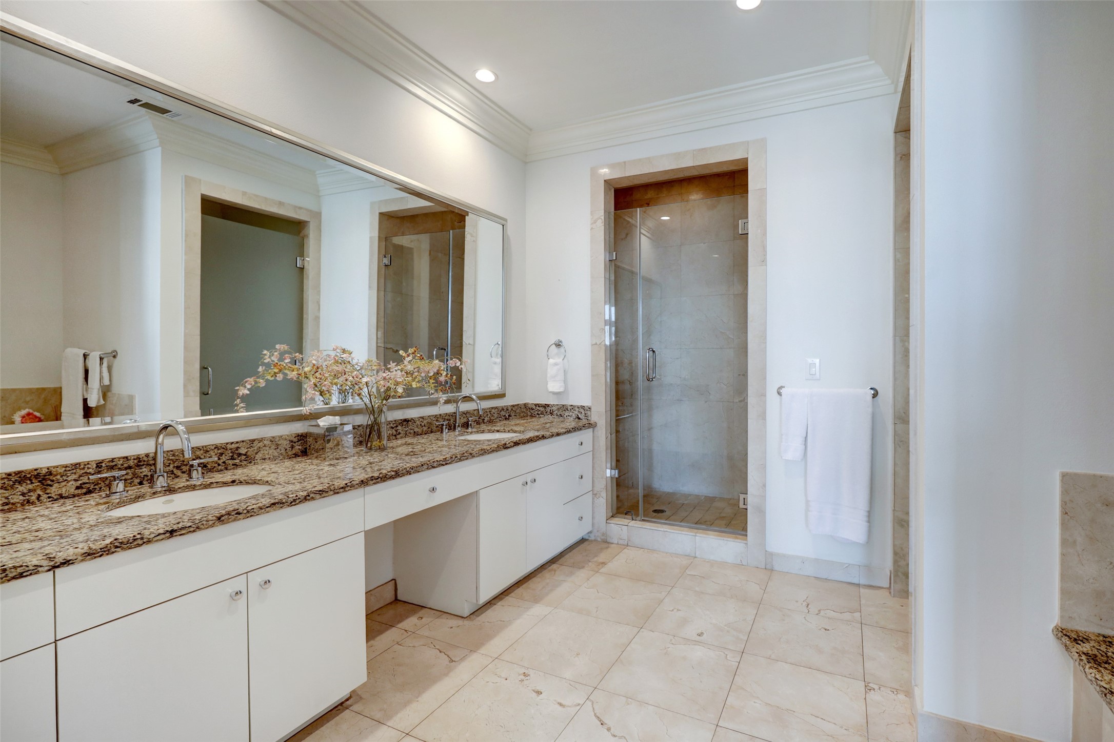 Primary bathroom with double sink vanity, large marble shower and granite counters.