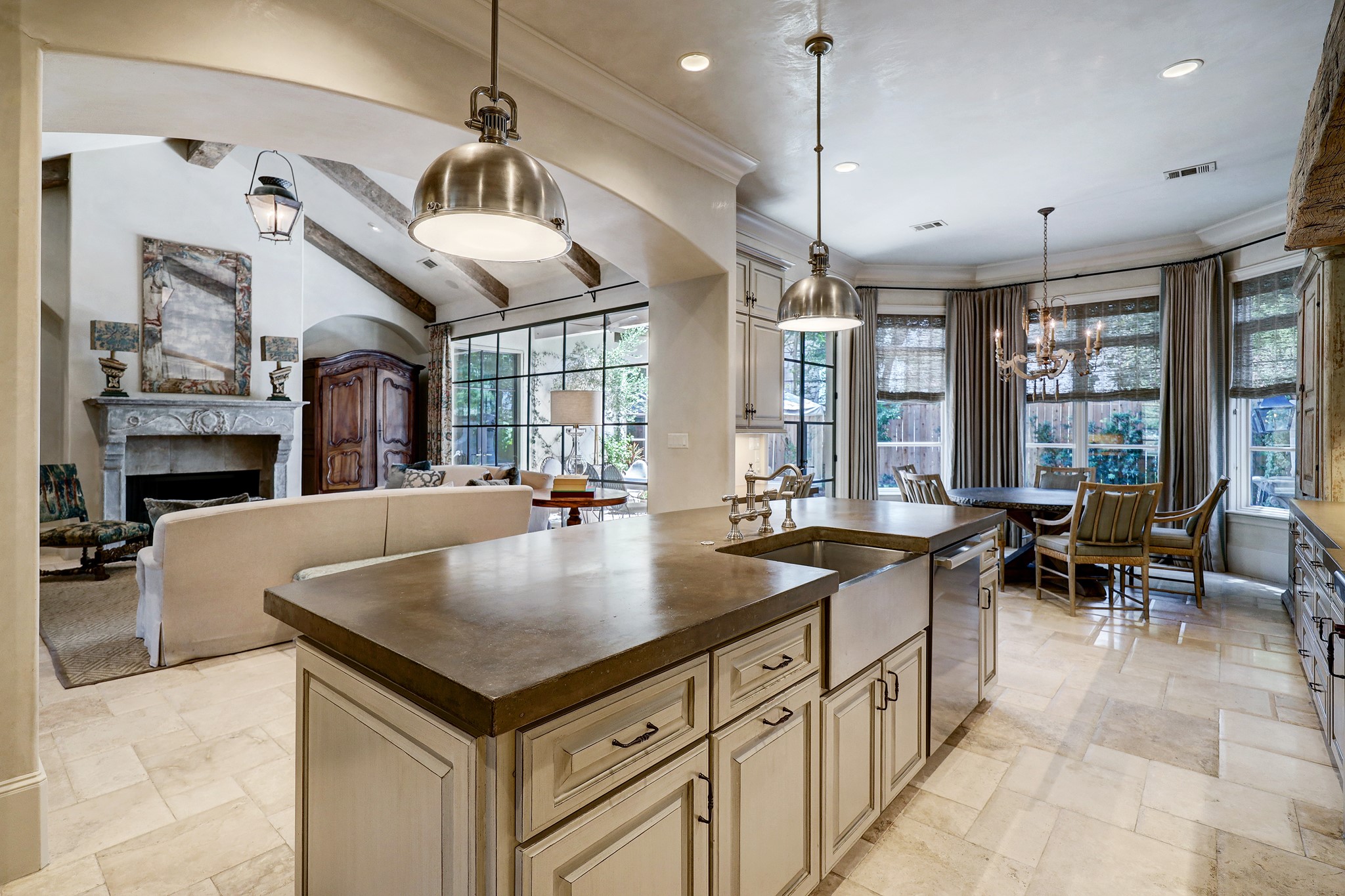 Functionality marries vintage elegance in the form of sleek and robust concrete countertop atop the working island, a stainless steel apron front sink, and yoke pendant lights hanging gracefully overhead, all surrounded by resplendent Segreto paint finishes.