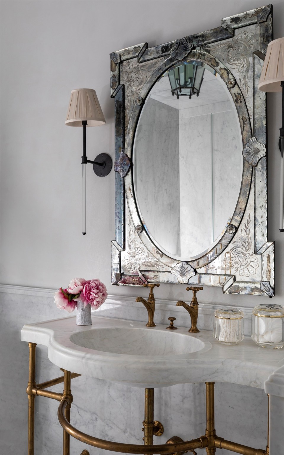 This impeccable ensuite bathroom epitomizes sheer sophistication with honed Carrera marble floor with slab shower walls, wainscot, and vanity. Quartz sconces, an antique Venitian mirror, and a polished brass electric towel warmer enhance the elegance.