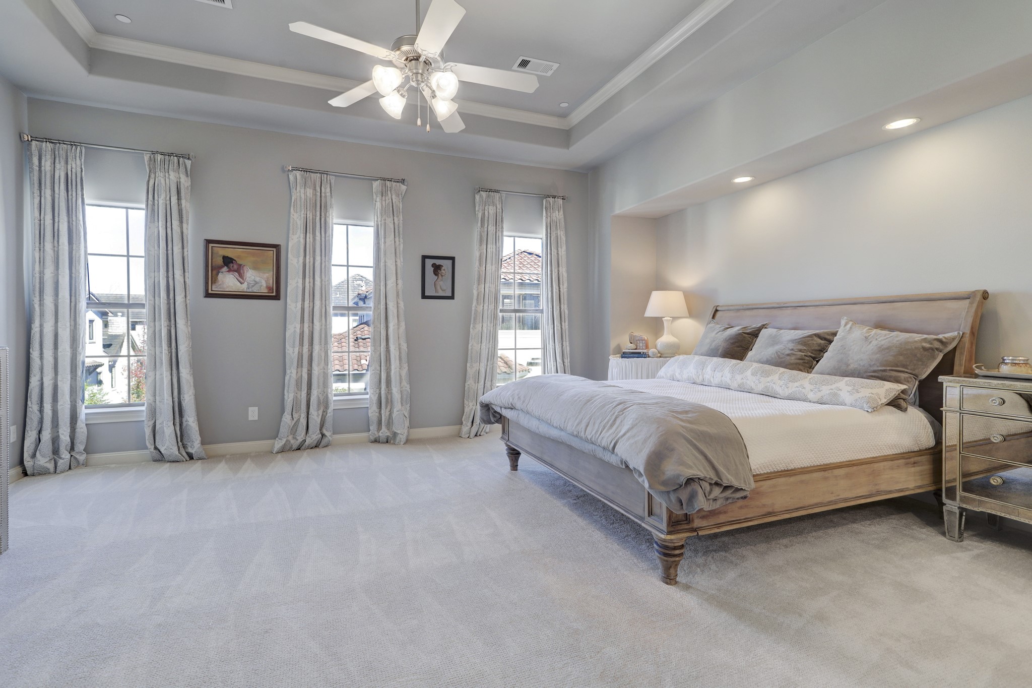 The primary bedroom features a tray ceiling, and an alcove bed wall with recessed lighting .