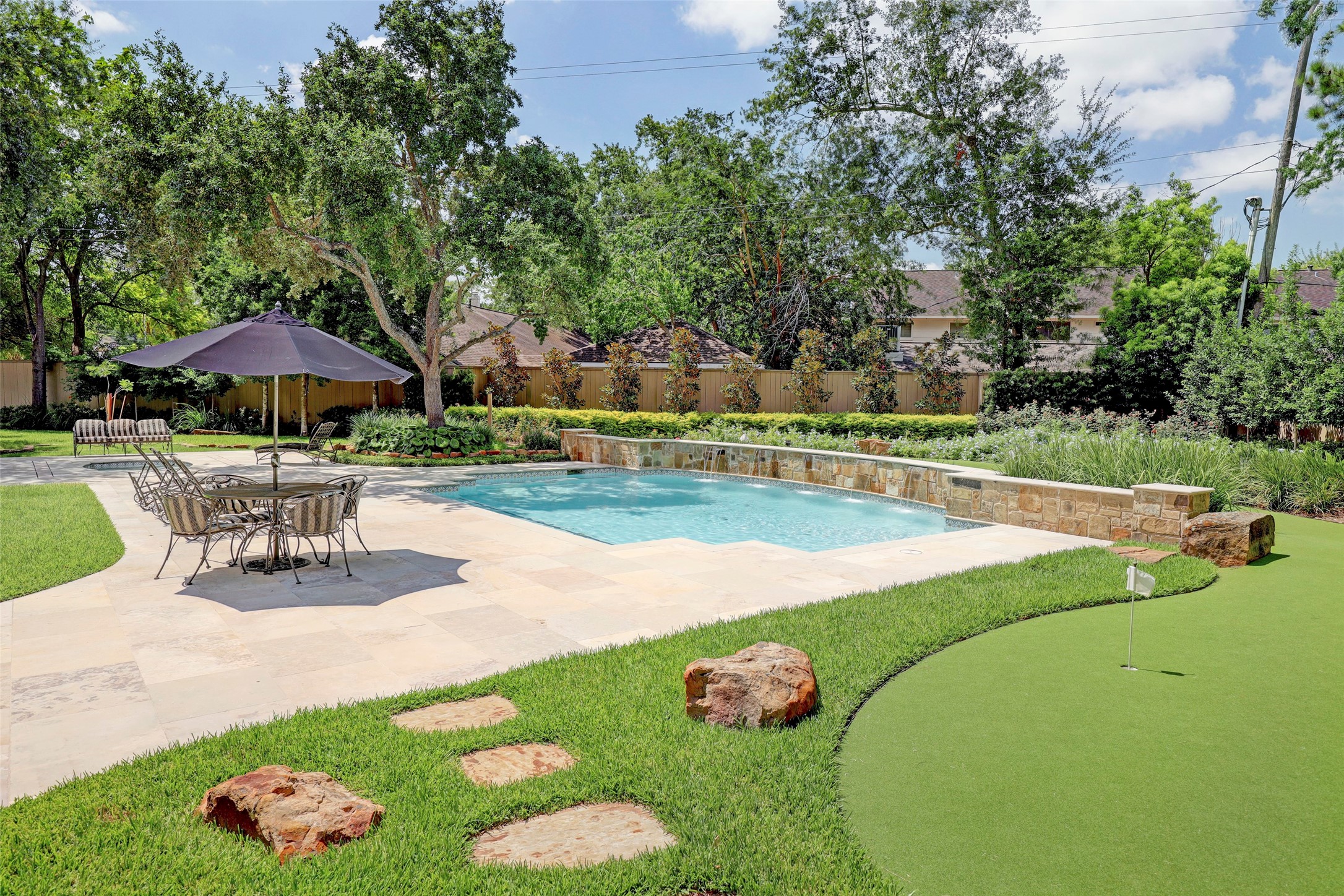 The inviting pool includes a water wall and is surrounded by a large patio to sit and relax and separate spa.