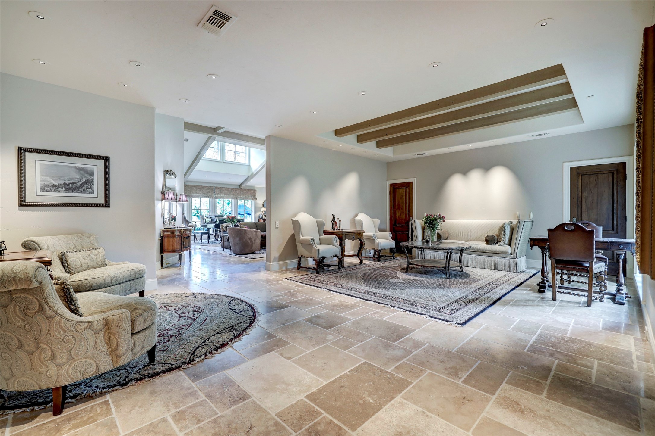 The formal living room features beamed ceiling, stone floor and art lighting.