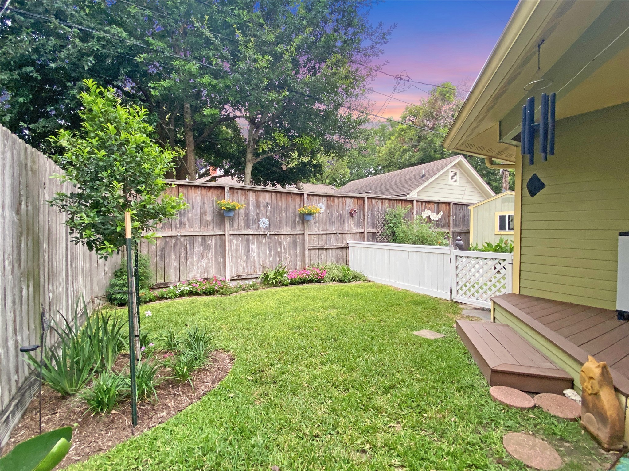 The backyard is currently split by the quaint, white fence leading to the vegetable garden.