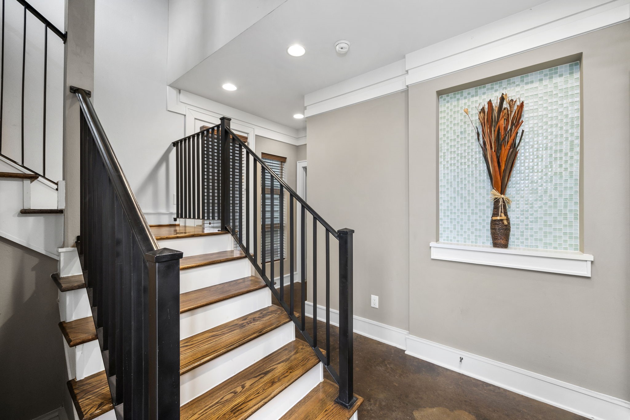 Grand Entry featuring a glass mosaic art niche & the wooden staircase w/wrought iron spindles, modern concrete flooring throughout the 1st Floor. 322 Patterson St., Houston, TX  77007