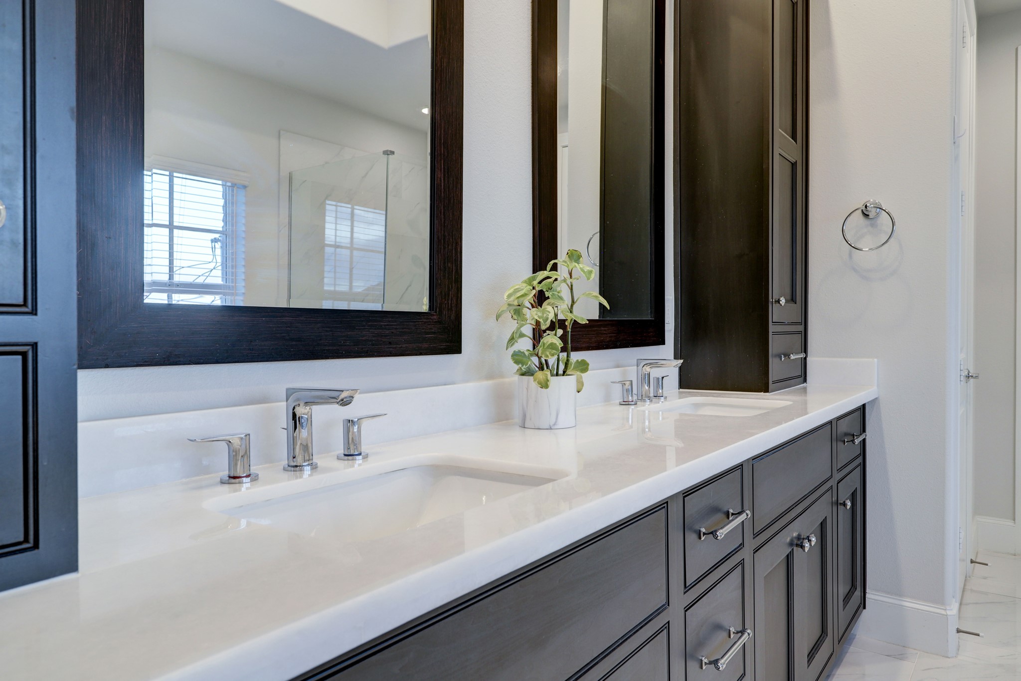 Dual vanities atop soft close drawers and cabinets with sleek chrome finished pulls and fixtures.