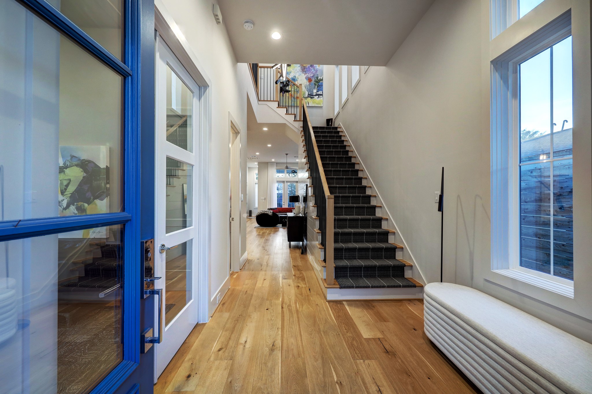 A charming blue entry door opens to a gracious foyer that introduces the home's soaring ceilings, oversized windows, wide-plank hardwood floors and beautiful millwork.