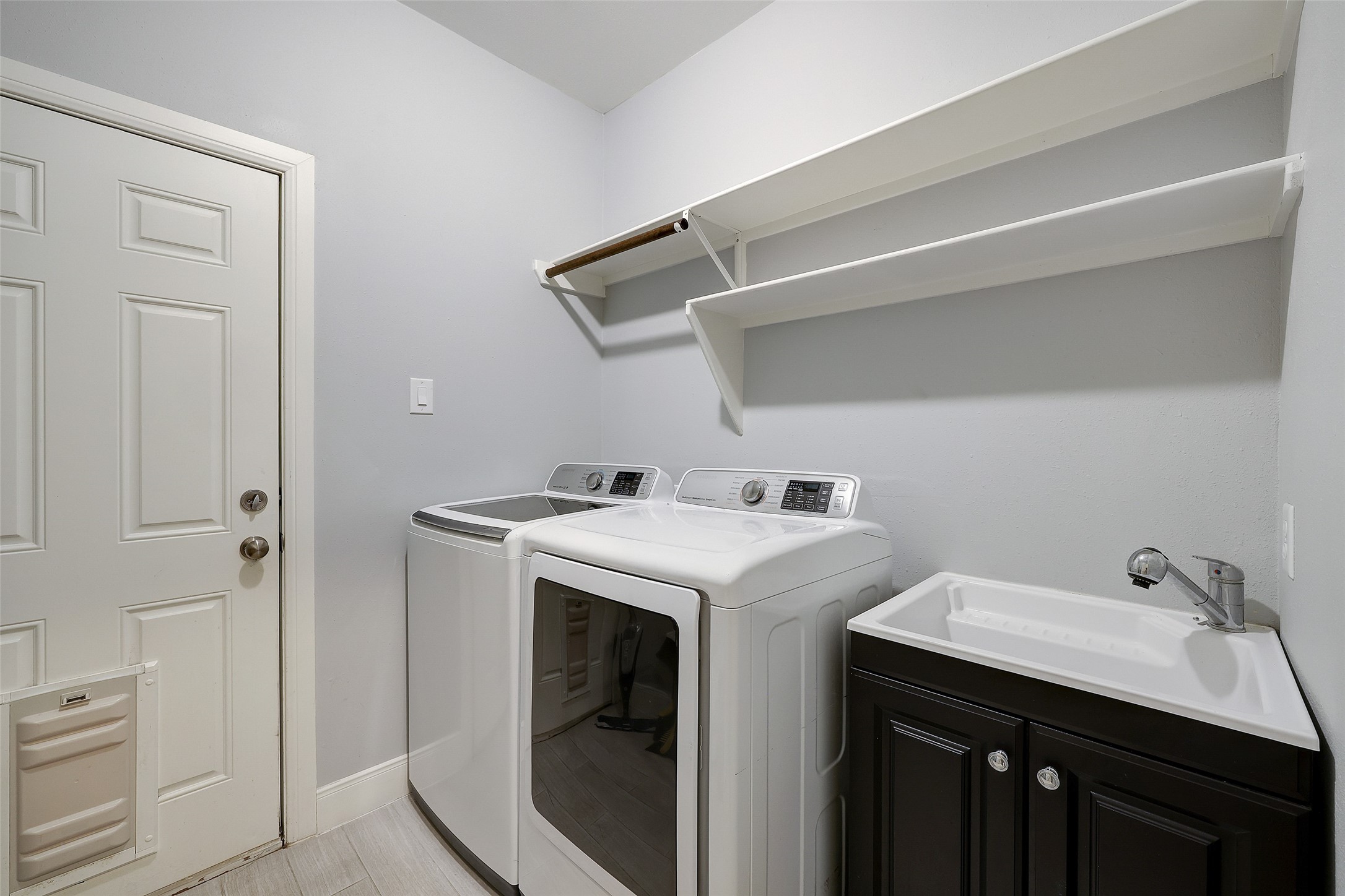 Utility room located in house with sink and access to outdoors.