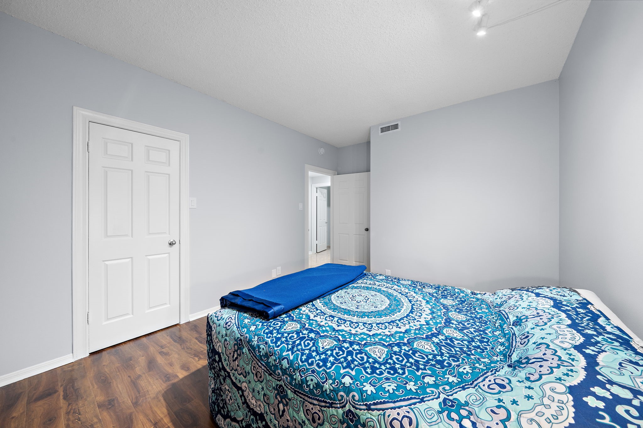 Bedroom featuring hardwood flooring, gray walls, recessed lighting, and two white doors.