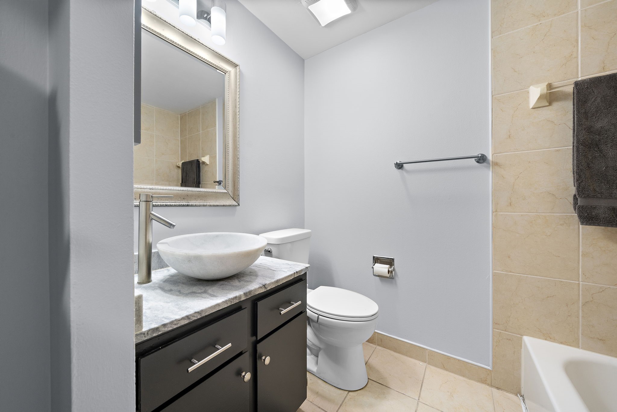 Modern bathroom with a vessel sink, granite vanity, tiled walls, and recessed lighting.