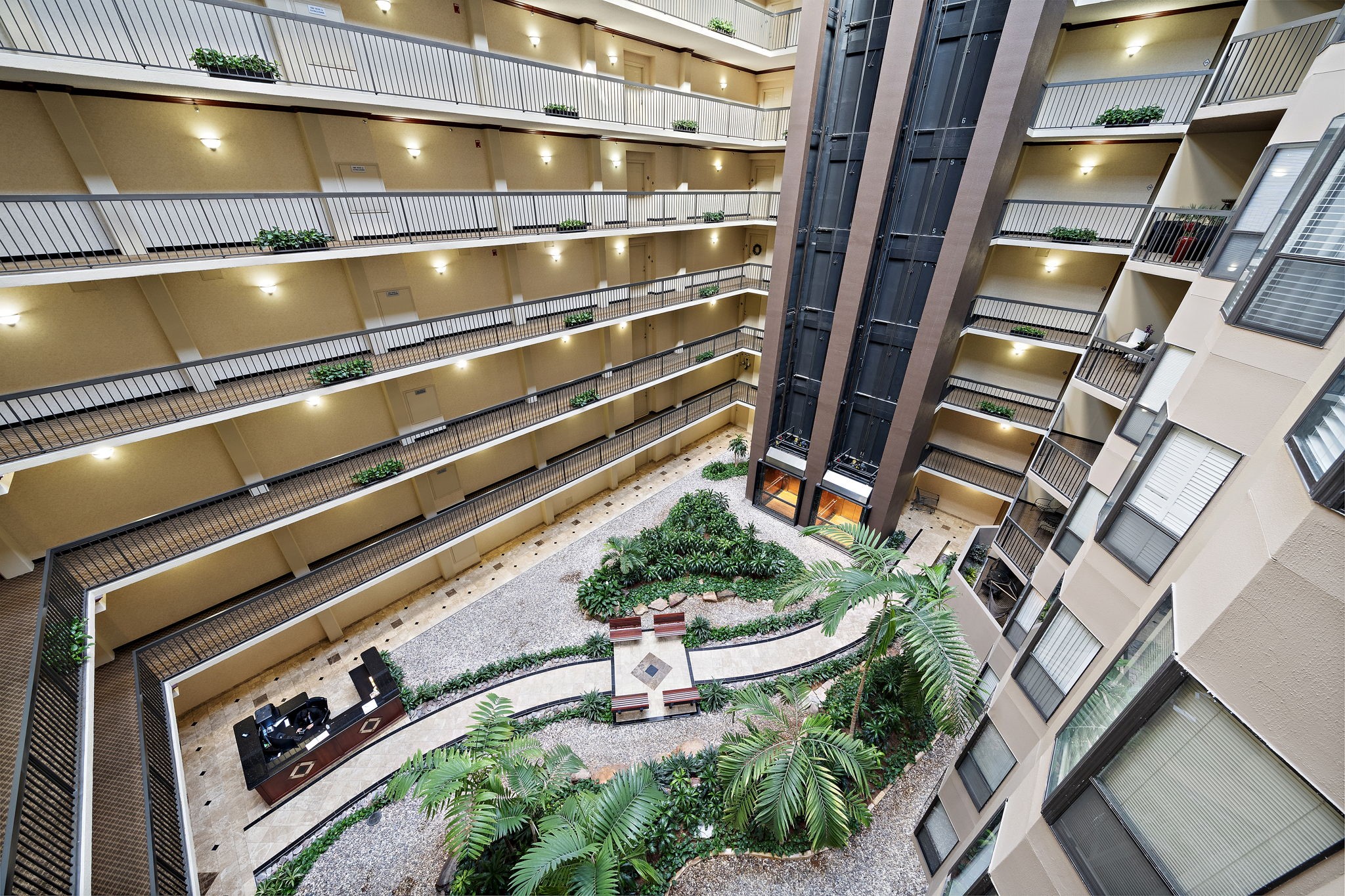 Atrium of a multi-level building with a lush indoor garden and seating area.