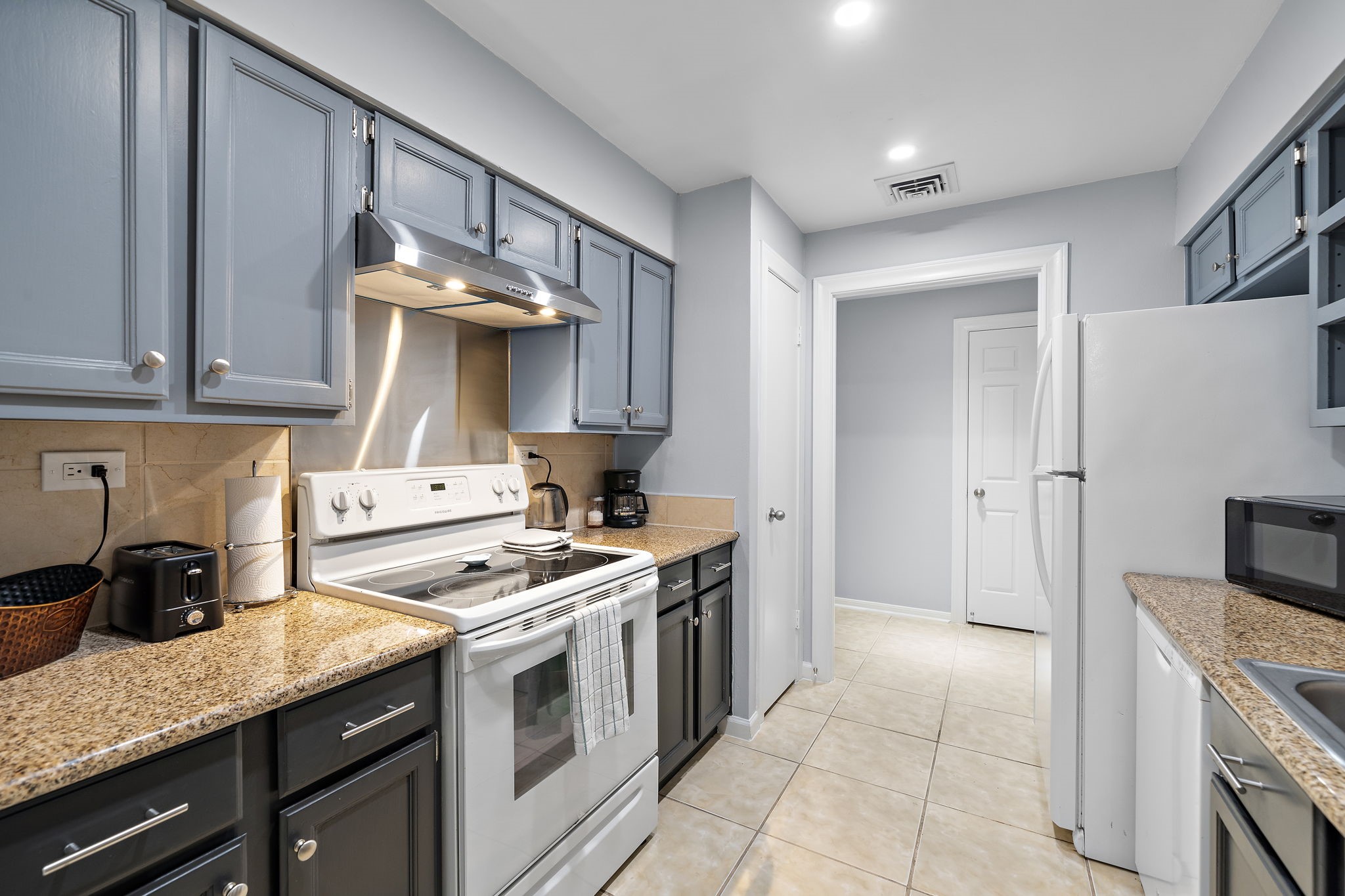 
Compact kitchen with blue cabinets, granite countertops, and stainless steel appliances.