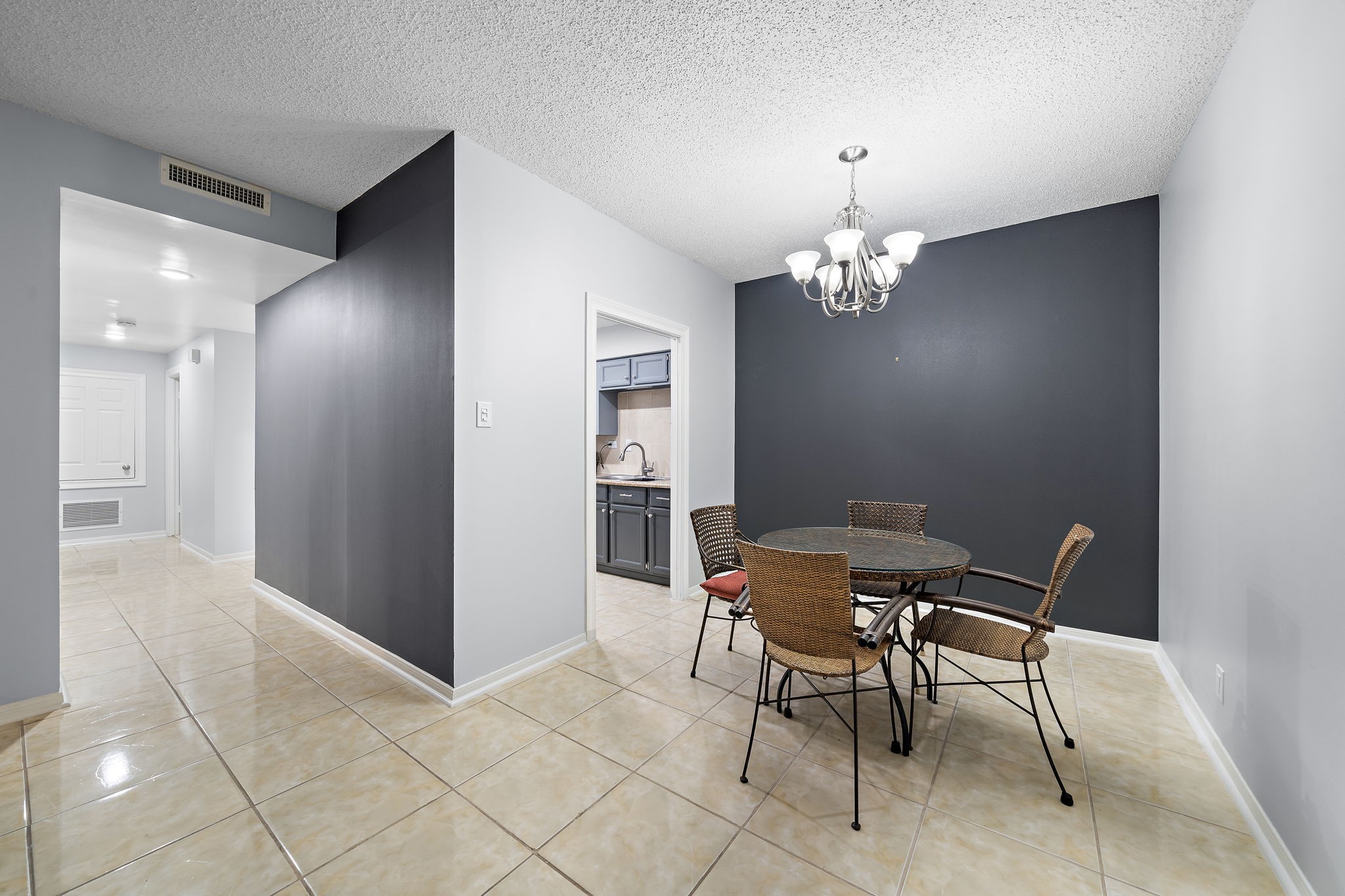 Dining area with a dark accent wall, tiled floor, and an opening to the kitchen.