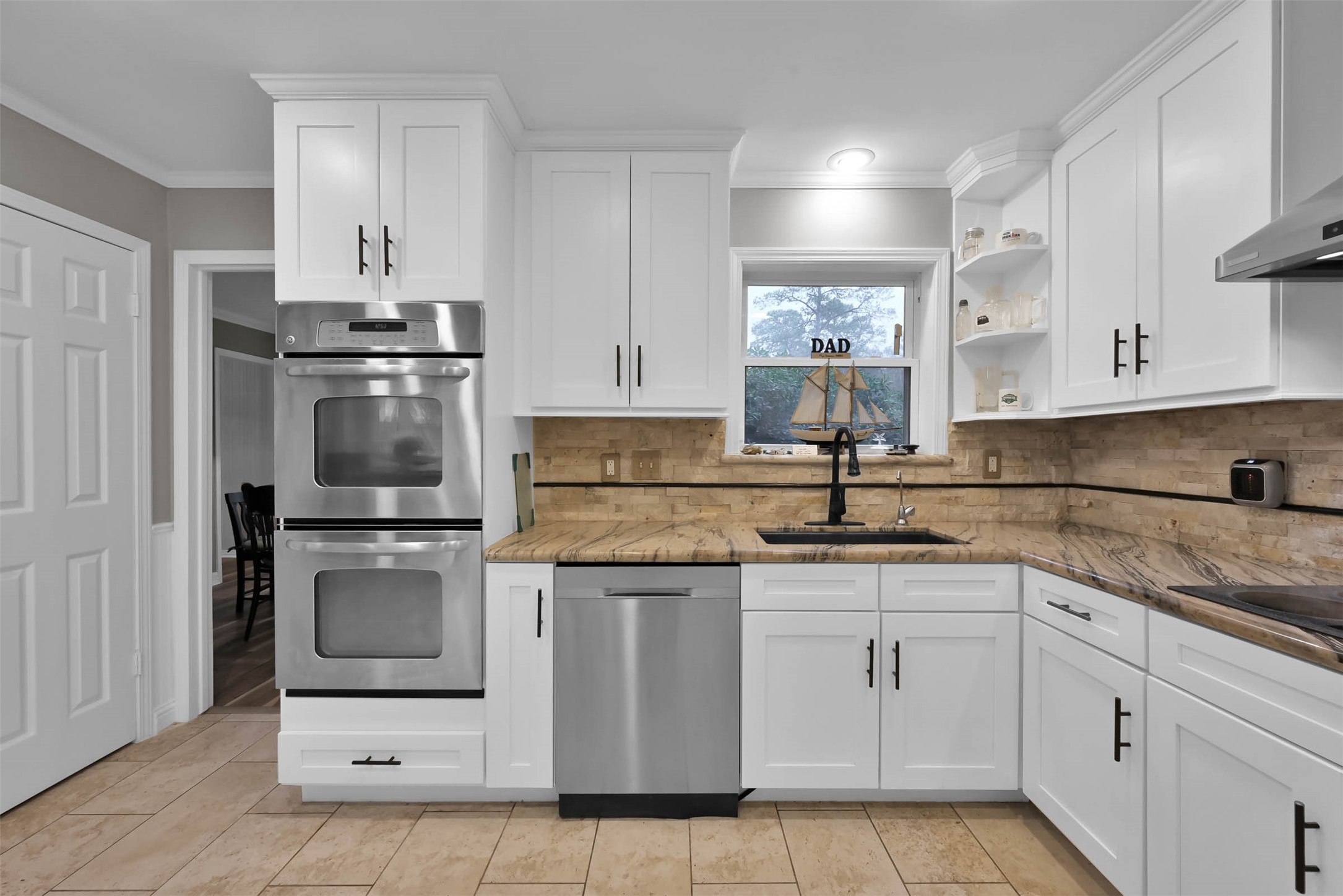There are double ovens and a granite composite sink with a recently replaced with a handsfree faucet. The door on the left leads to a walk-in pantry.