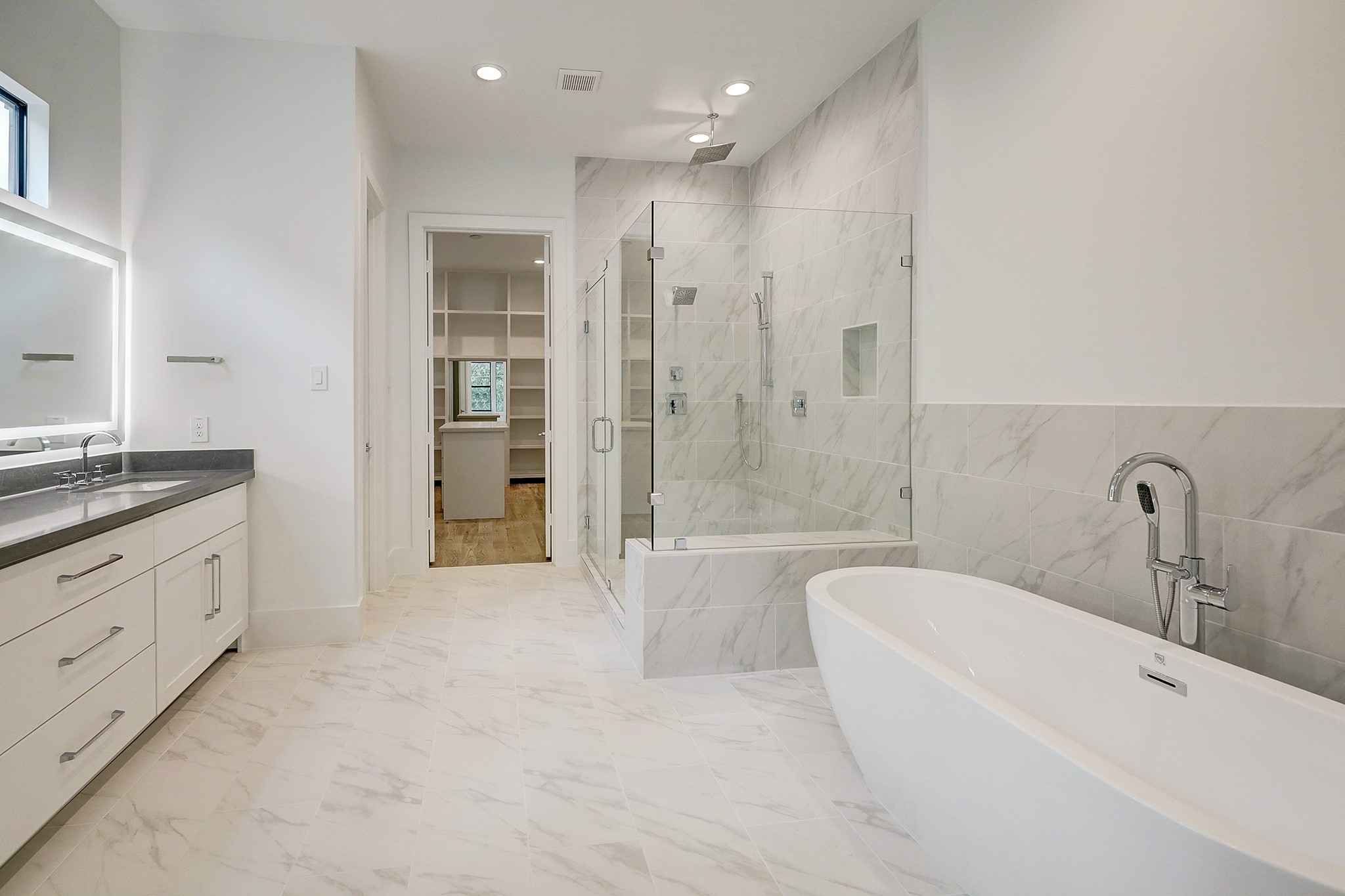 Primary bathroom suite with double sinks, LED mirrors, and separate soaking tub and shower