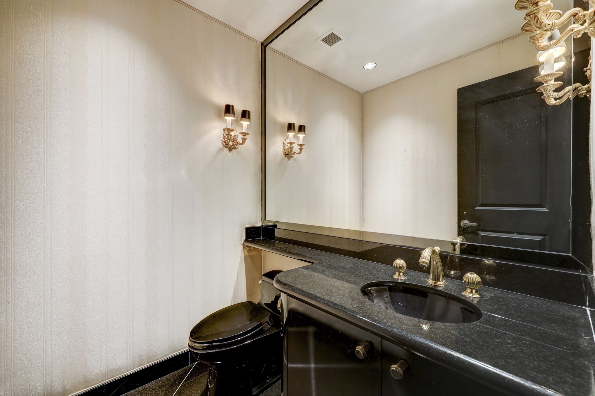The powder room, which is located just off the Entry, features black granite floors and fabric wallpaper.