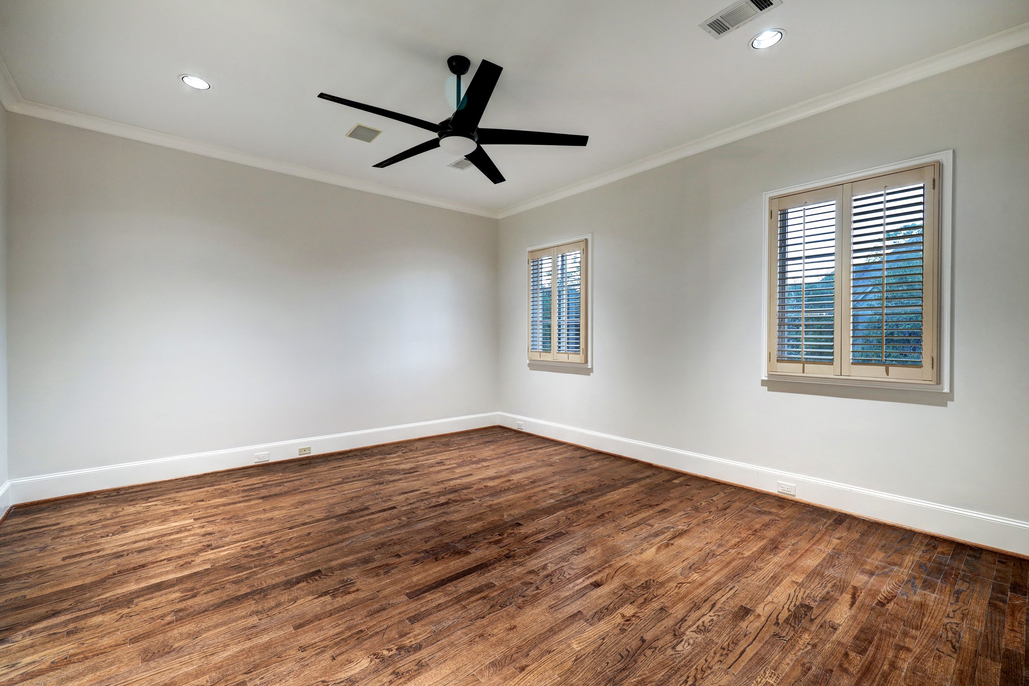 This Secondary Bedroom features wood floors, crown molding & baseboards, windows with plantation shutters and an en-suite bathroom with walk-in closet.