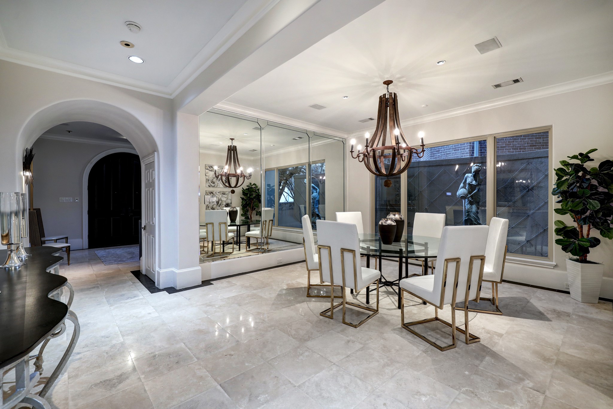 The Formal Dining Room is centrally located and features tile floors, crown molding & baseboards, a mirrored wall, windows overlooking the side courtyard with a fountain and access to the Wet Bar.