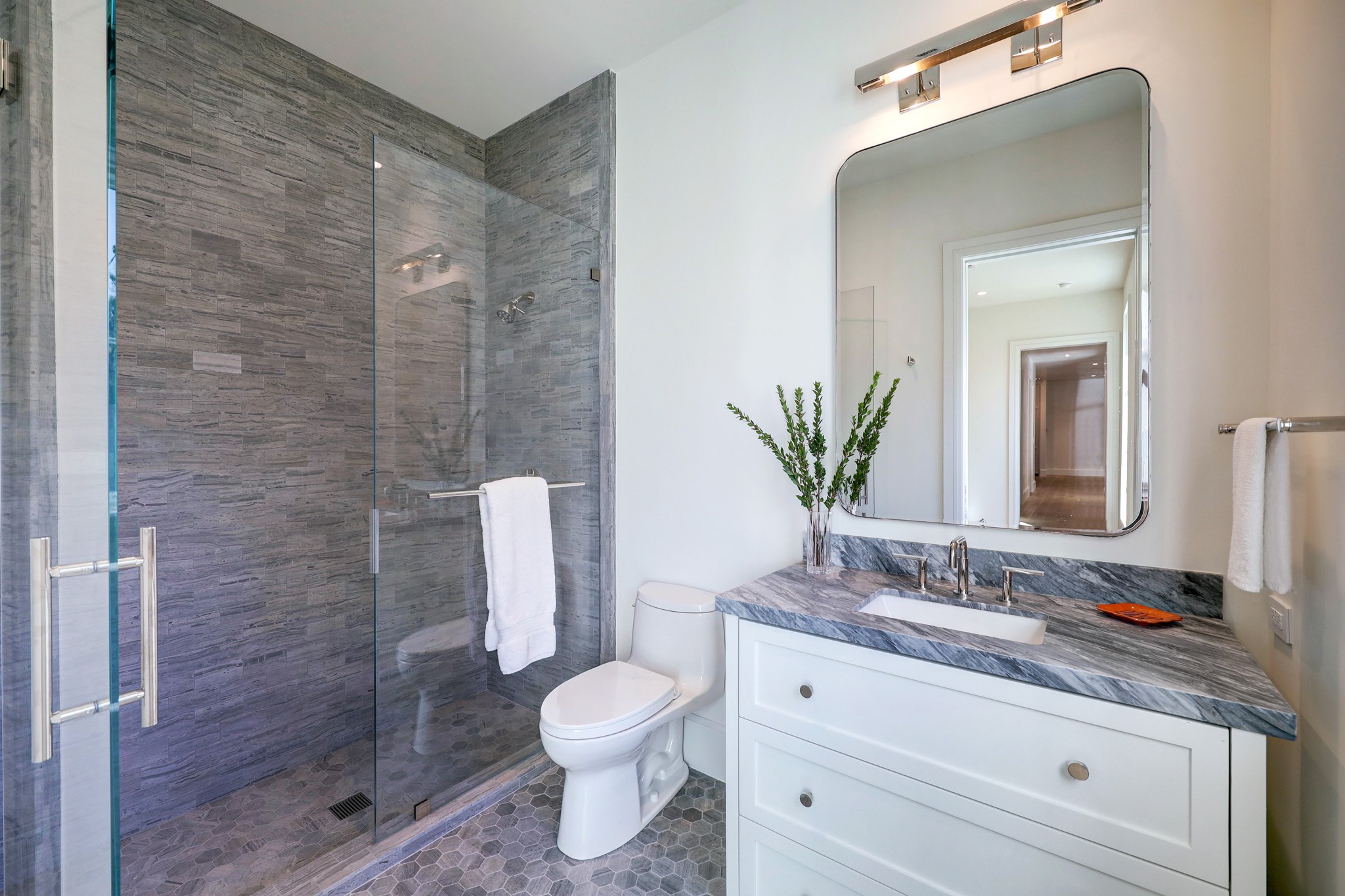 The secondary full bathrooms showcase floor-to-ceiling backsplash, a seamless glass enclosure, and custom mosaic tile for a distinctive touch.