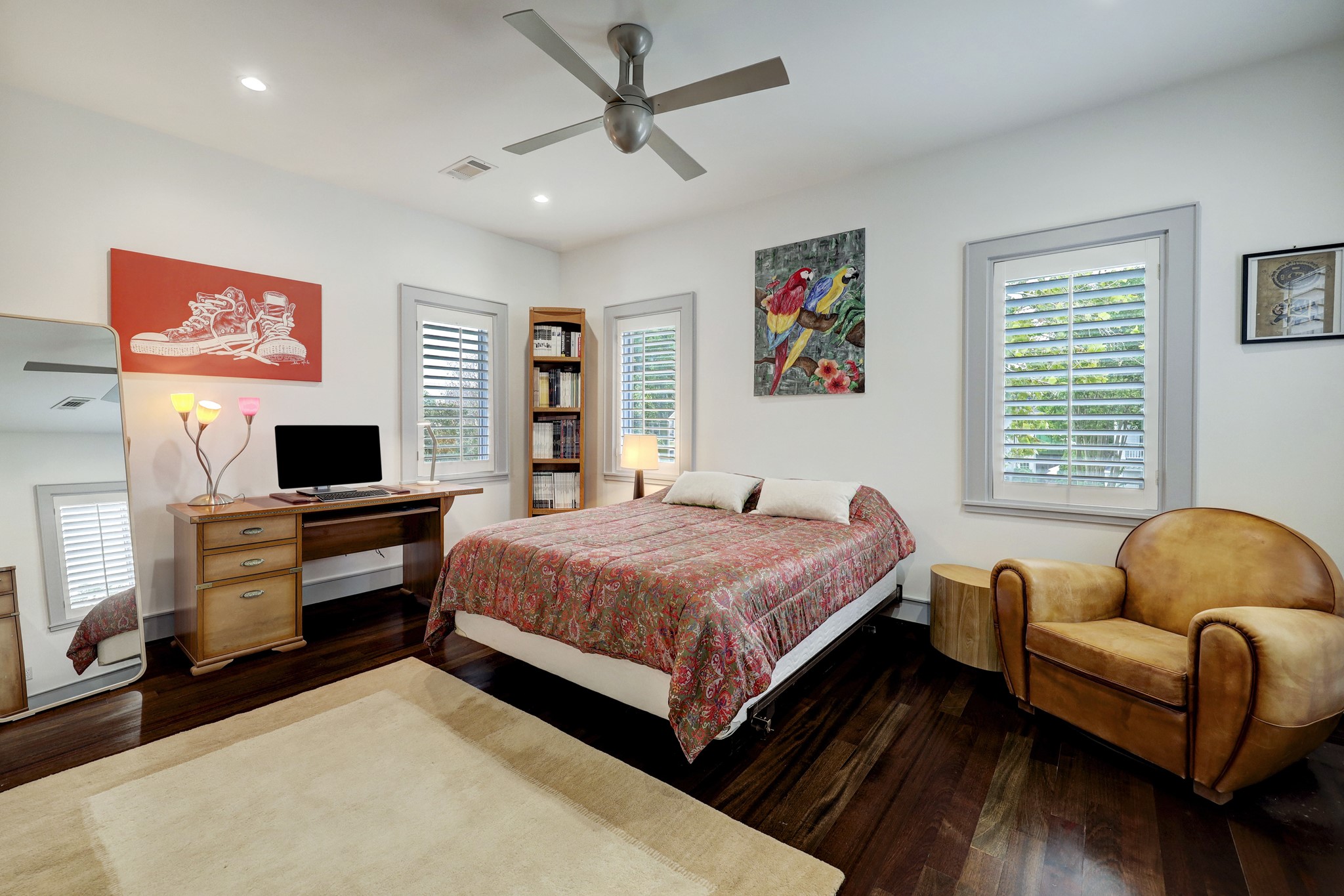A comfortable bedroom with plantation shutters and handsome hardwood floors.


