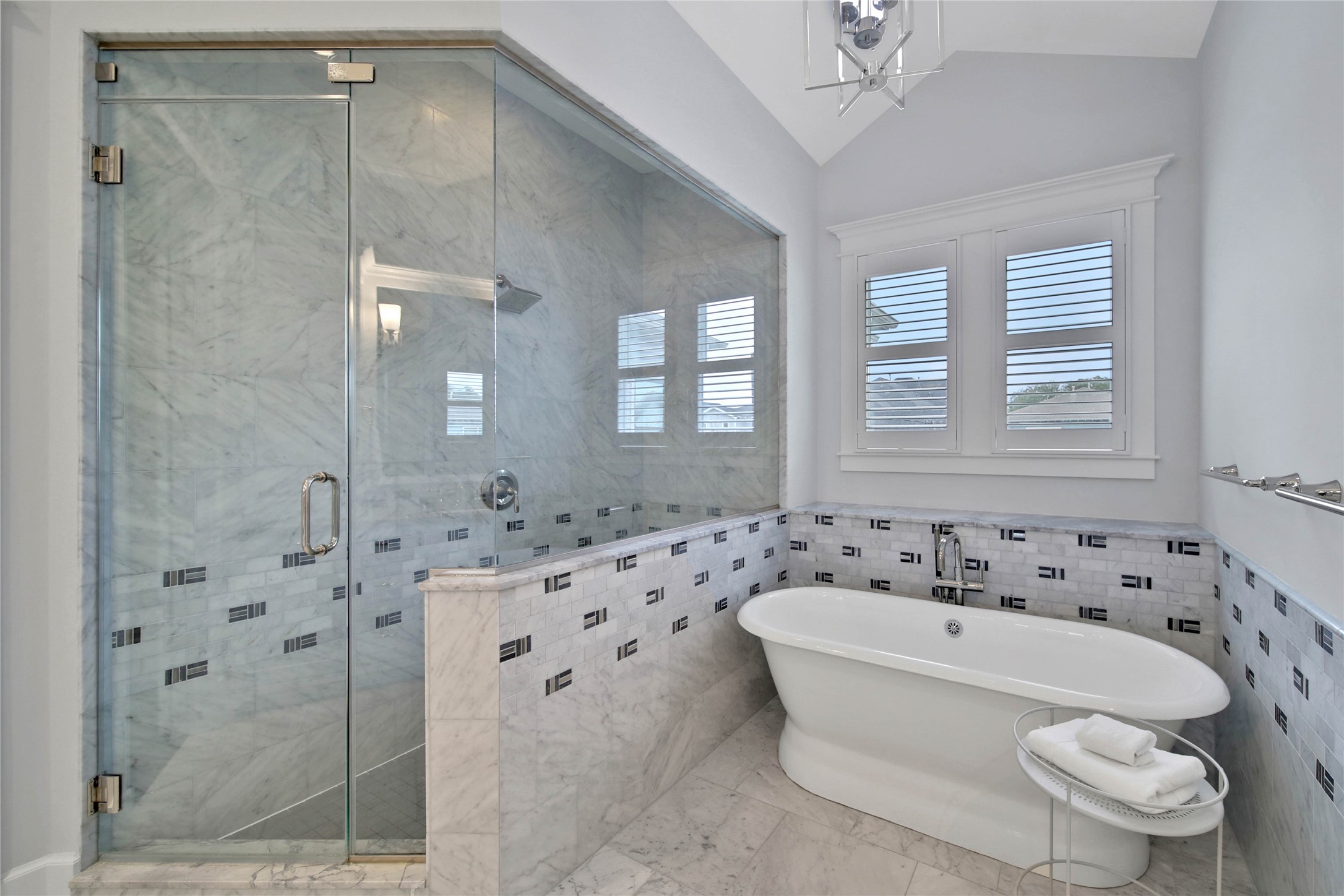 Experience luxury and relaxation in the primary bathroom, featuring a spacious walk-in glass shower and a soothing tub.