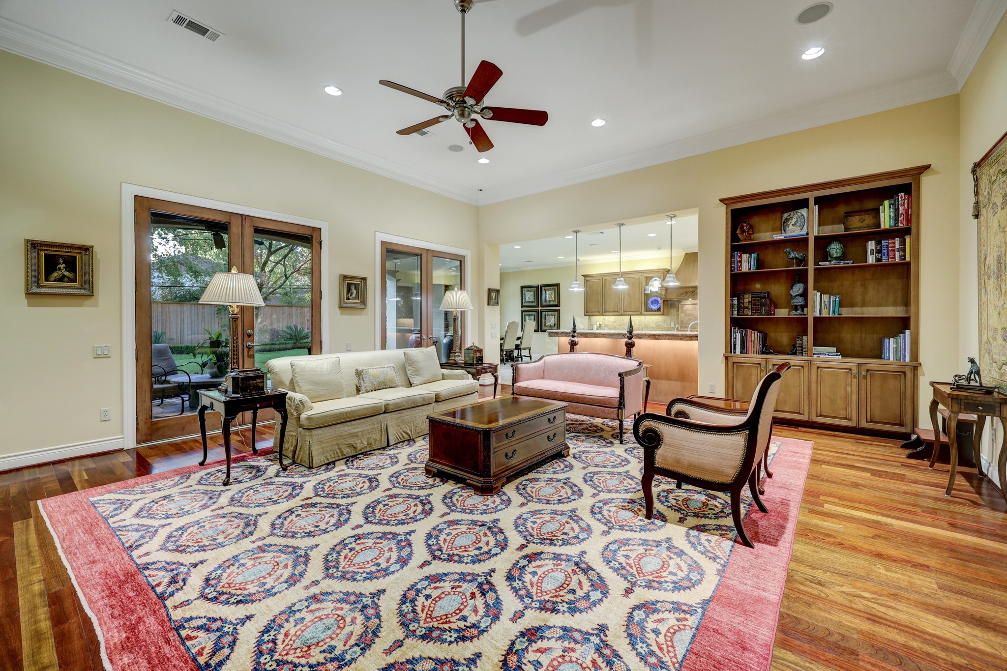 The Family Room [25 x 20] features hardwood floors, crown molding and baseboards, ceiling speakers, two walls of built-ins, gas fireplace with tile surround and wood mantle, and access to the covered patio/summer kitchen.