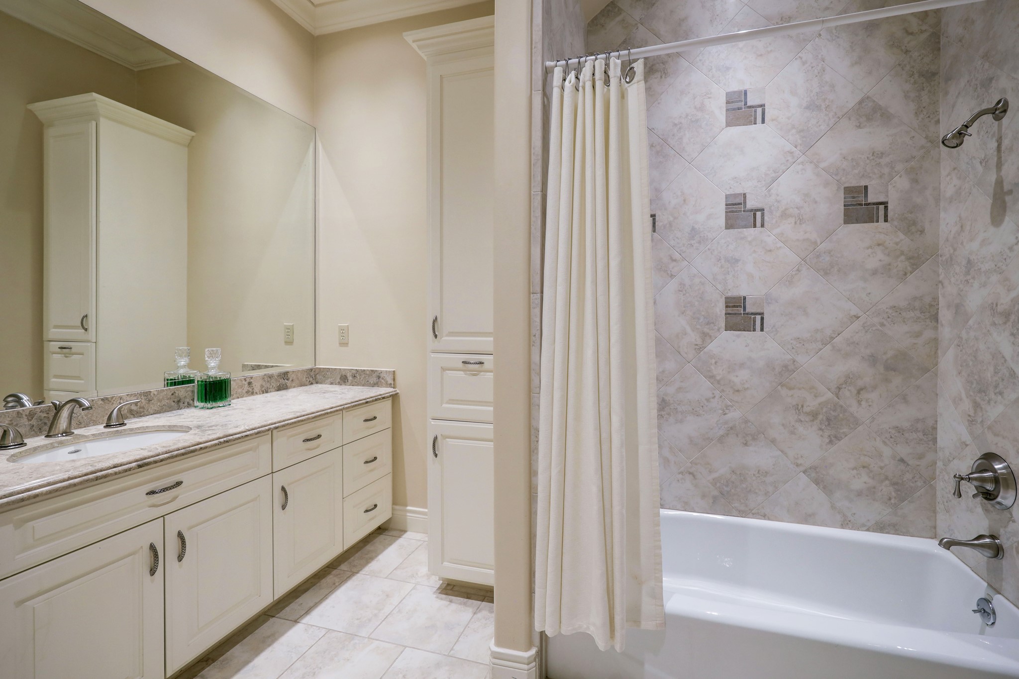 This Secondary Bathroom [13 x 6] features tile floors, marble countertop and backsplash, built-in linen storage and laundry hamper, and tub/shower combo with tile surround. This bathroom is meant to service the Home Theatre/Game Room.