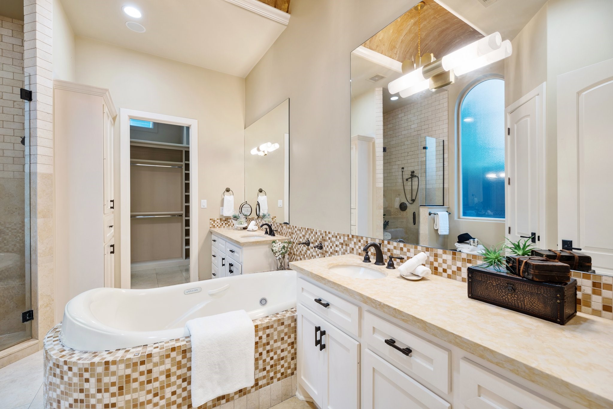 PRIMARY BATHROOM - Luxurious bathroom with leathered stone countertops, air jet tub with tile surround, separate walk-in shower, double vanities and linen storage.