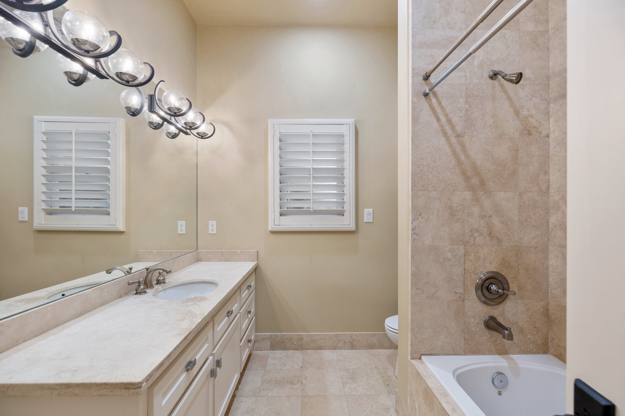 GUEST SUITE BATHROOM - Spacious bathroom with stone countertops and tub/shower combo with stone tile surround.