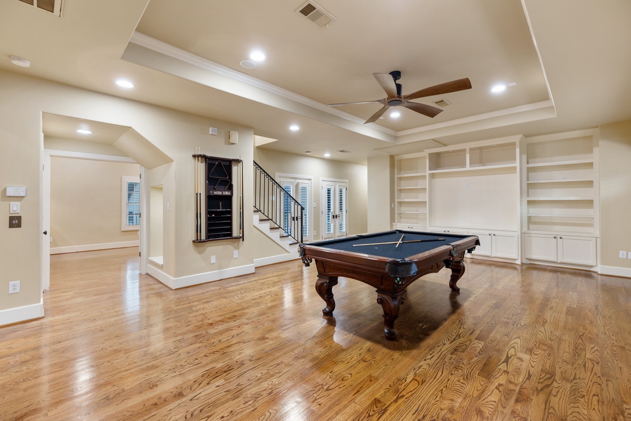 GAMEROOM - Game room with oak floors, tray ceiling, crown molding and built-in entertainment center.