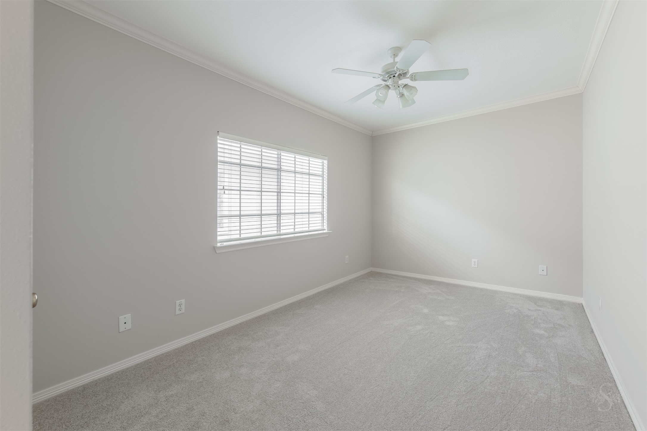 This secondary bedroom features a high ceiling with crown molding and a ceiling fan, window with custom blinds and soft coloring to create a warm and cozy environment. There's plenty of room for a bed, dresser and student desk.