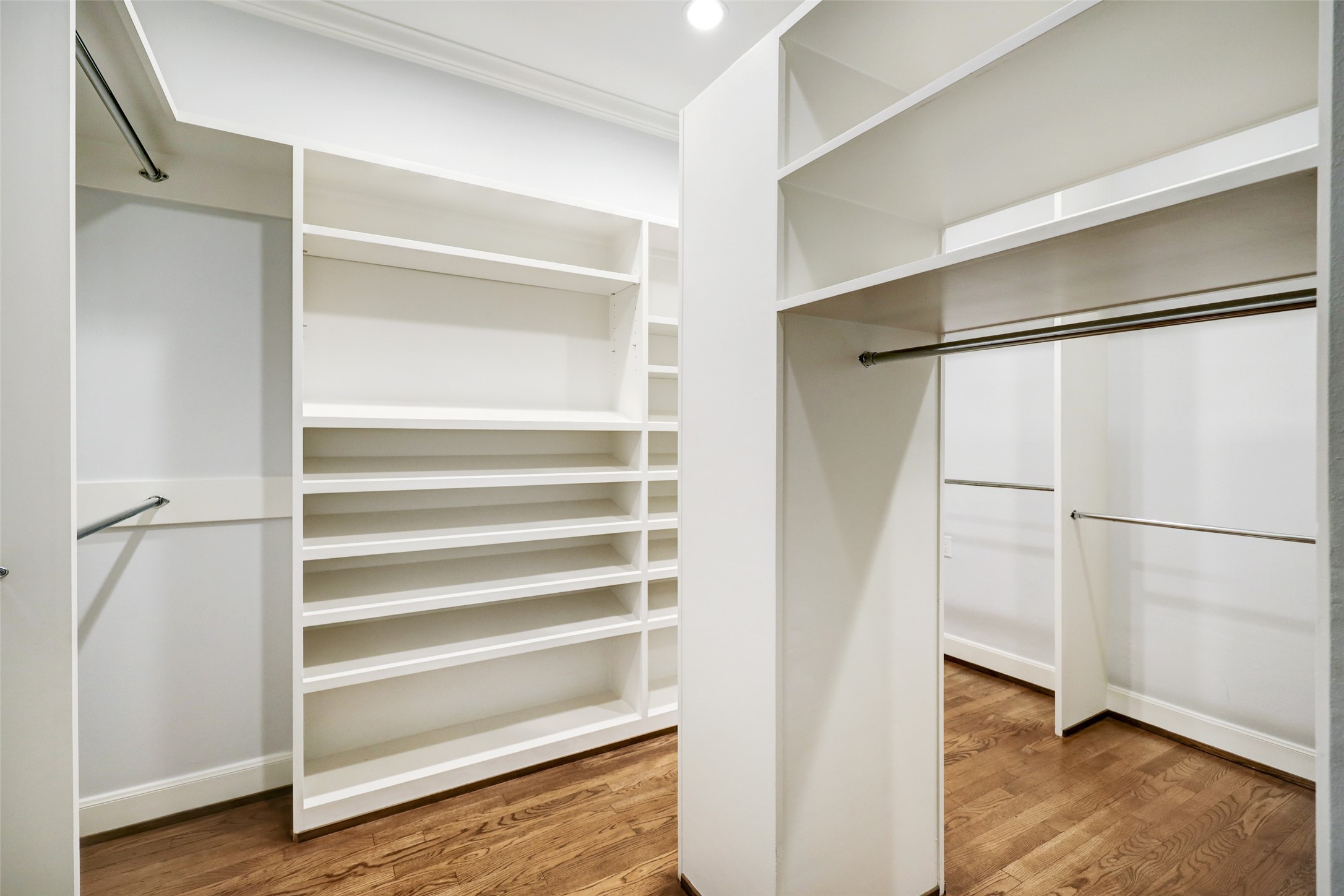 One of the two oversized primary bedroom walk-in closets is a haven of organization and style. It features plenty of racks and shelves, providing ample space to neatly arrange and showcase your wardrobe and accessories.