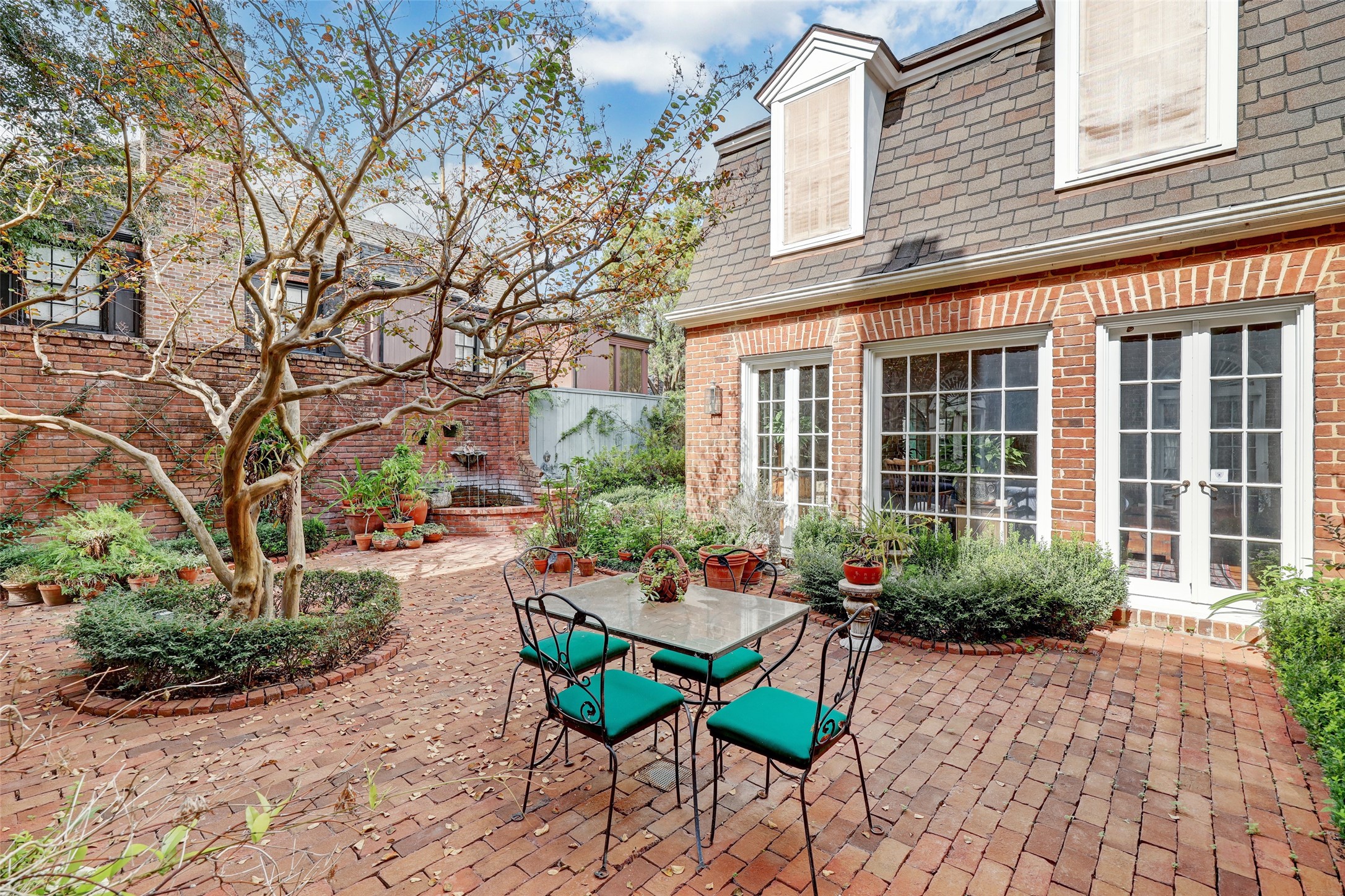 The first of two rear courtyards is nestled between the wings of the formal living room and the den and boasts a charming brick patio, tasteful landscaping and a fountain, making it a perfect spot for quiet contemplation or social gatherings.
