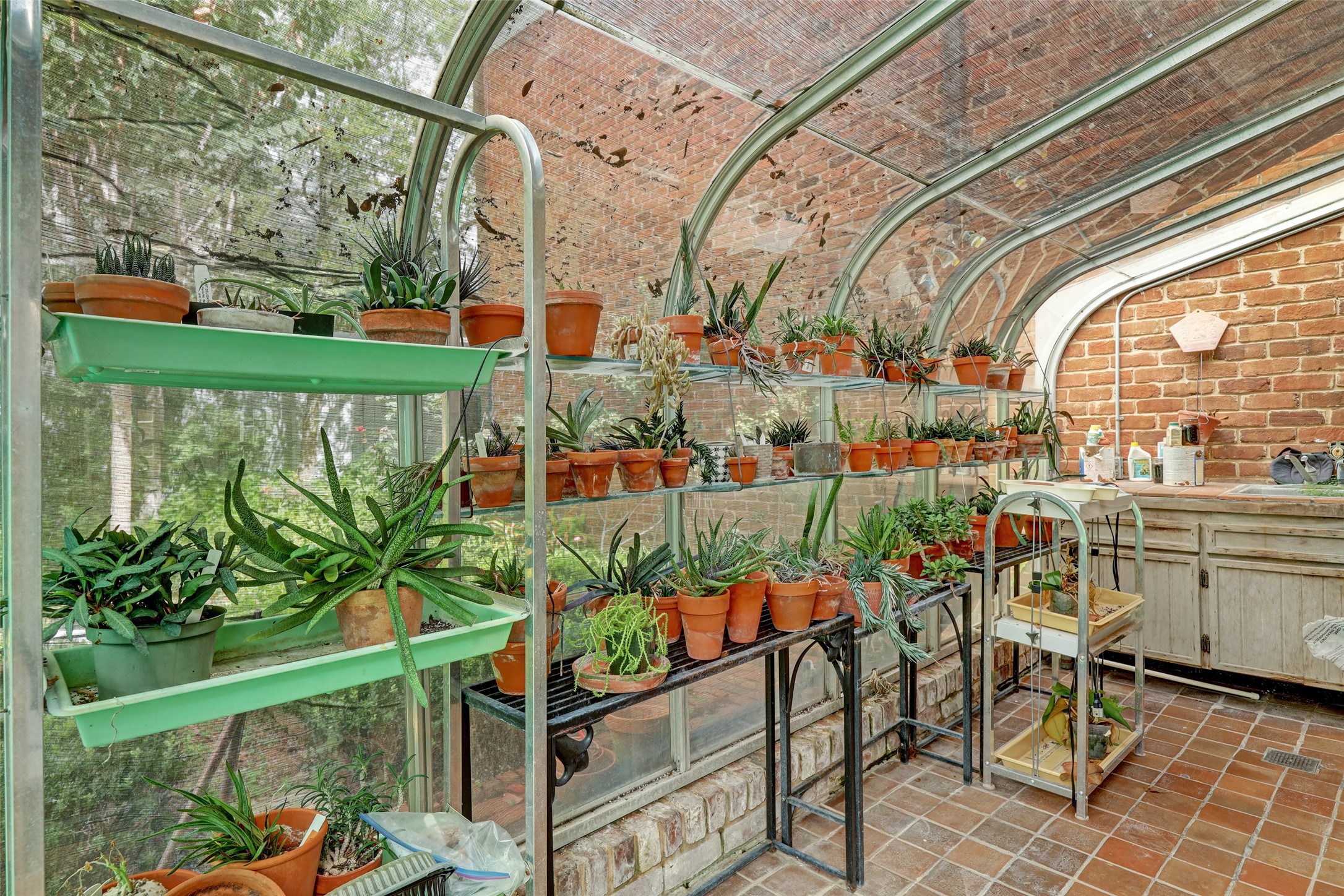 At the rear of the home, a greenhouse stands as a testament to the homeowner's love for gardening and nurturing plants.