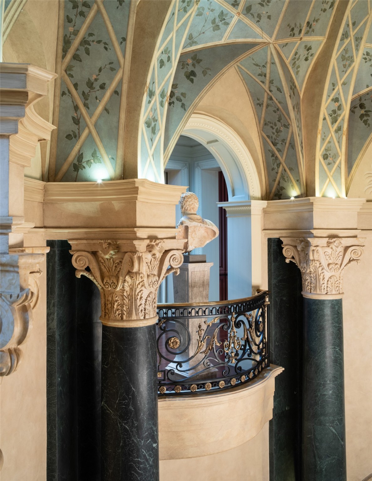 Iron scrollwork on the Juliet balconies matches the ornate detail of the Corinthian capitals.