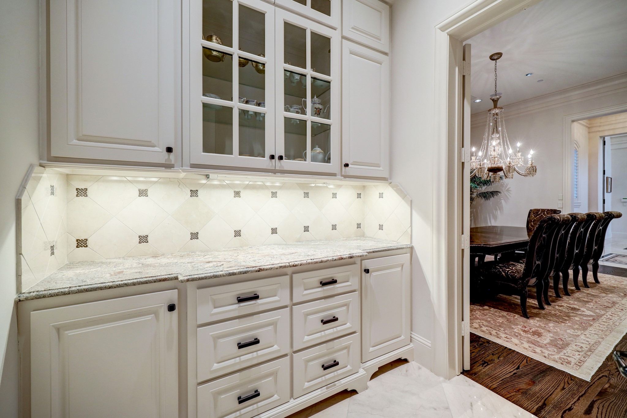 The Butler's Pantry is located between the Formal Dining Room and Kitchen and offers a granite countertop with tile backsplash, overhead and undercounter cabinets/drawers offering great prep and storage space