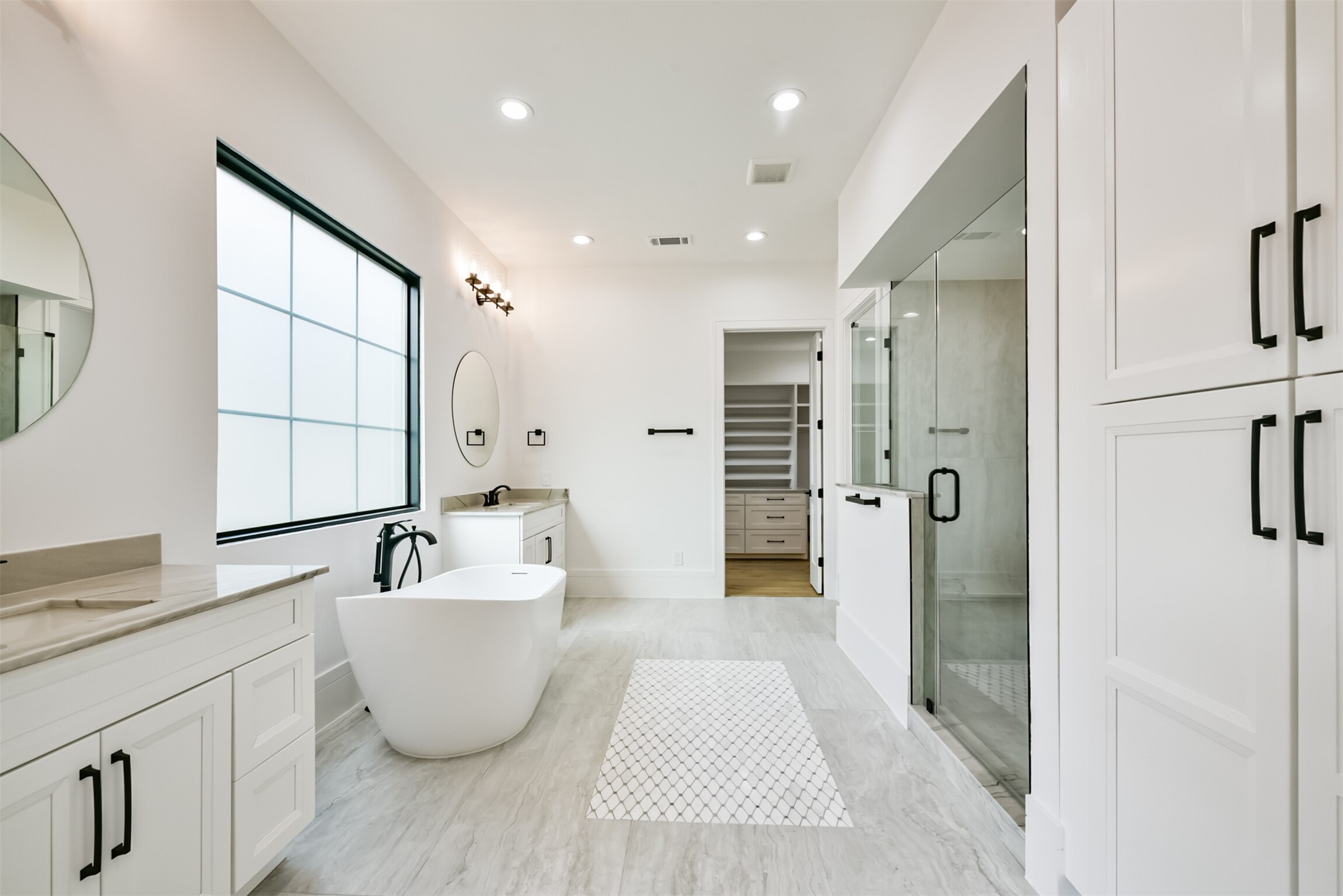 Primary Bathroom featuring His and Hers Sink Areas, Frameless Shower, Freestanding Bathtub and more!